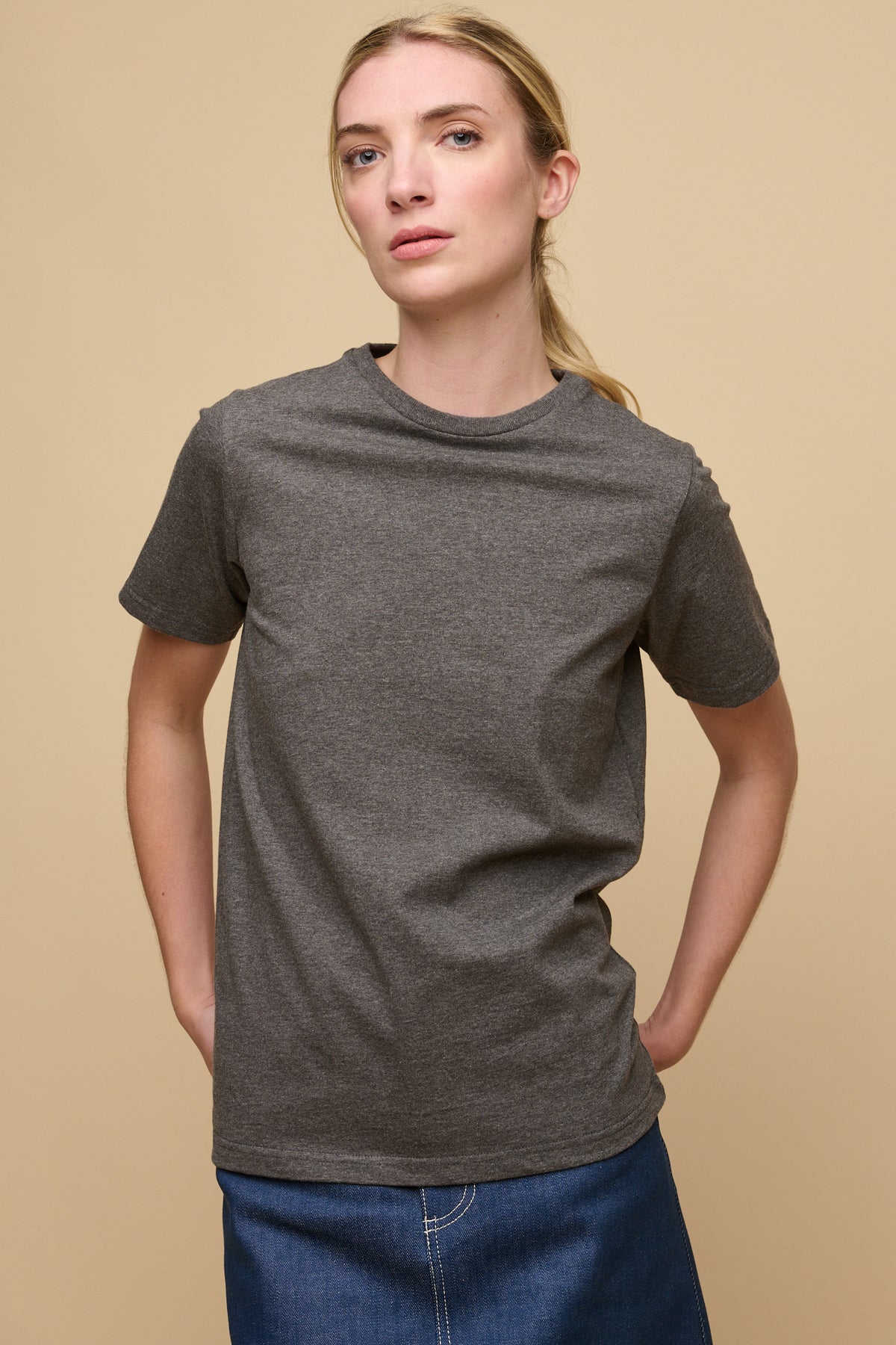 Thigh up image of female wearing short sleeve crew neck t shirt in charcoal