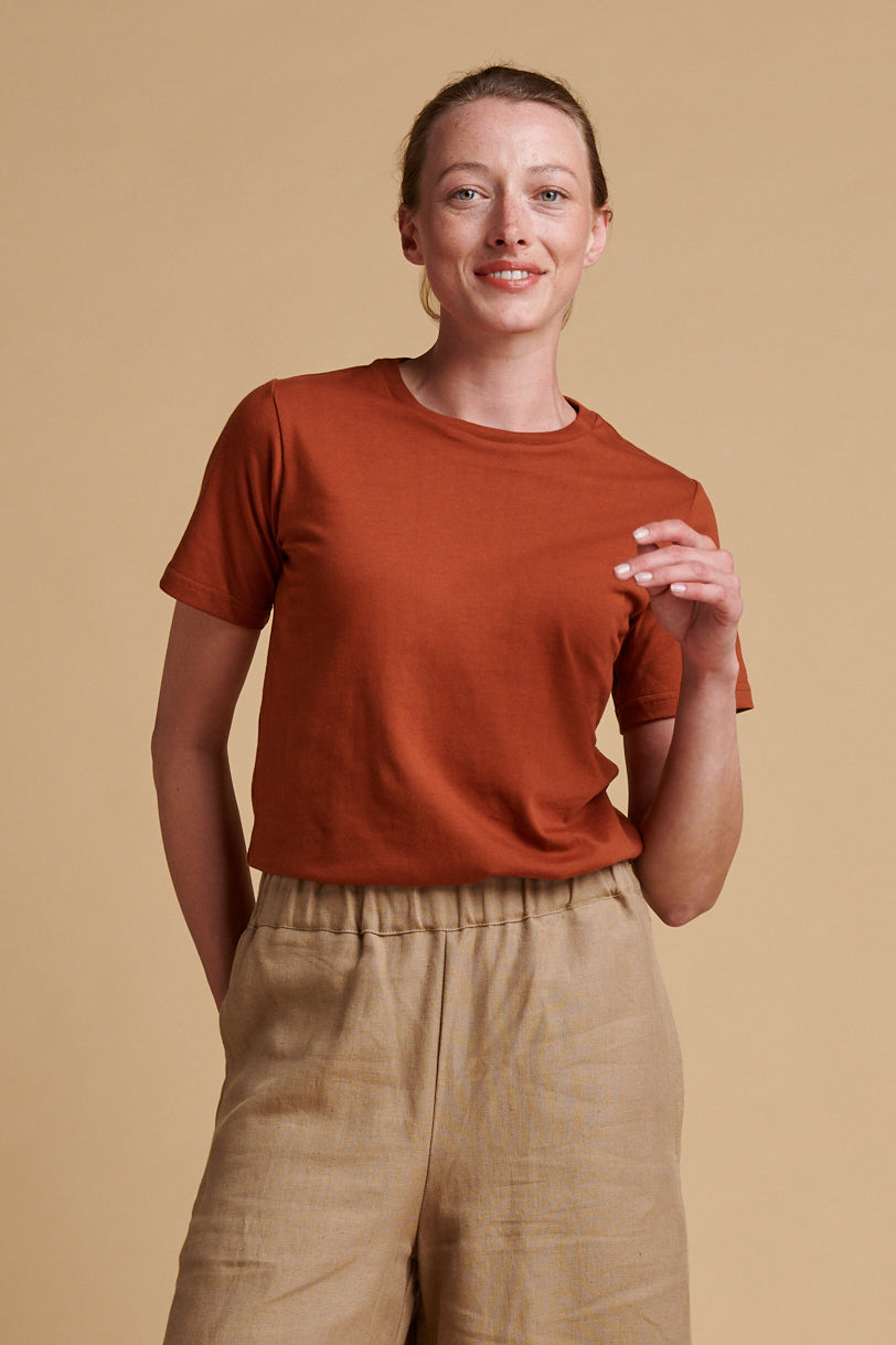 Female wearing short sleeve, crew neck t shirt in cinnamon tucked into short pj trousers in truffle linen.