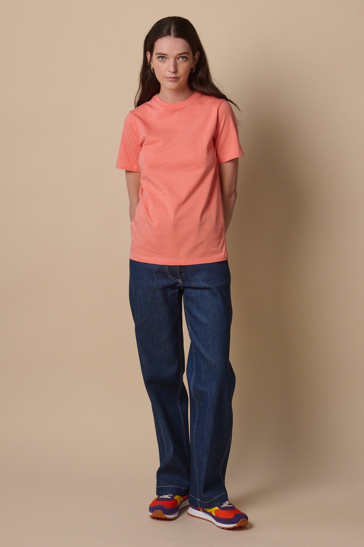 Full body image of female wearing short sleeve t shirt in peach