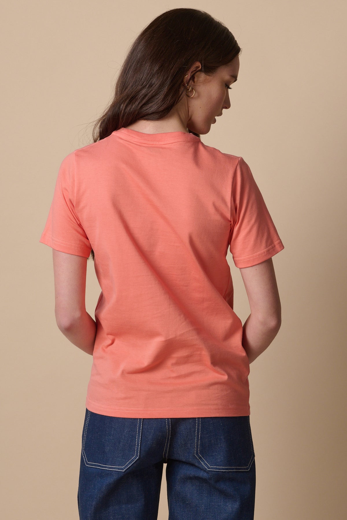 Back of female wearing short sleeve t shirt in peach