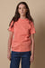 thigh up image of brunette female wearing short sleeve t shirt in peach