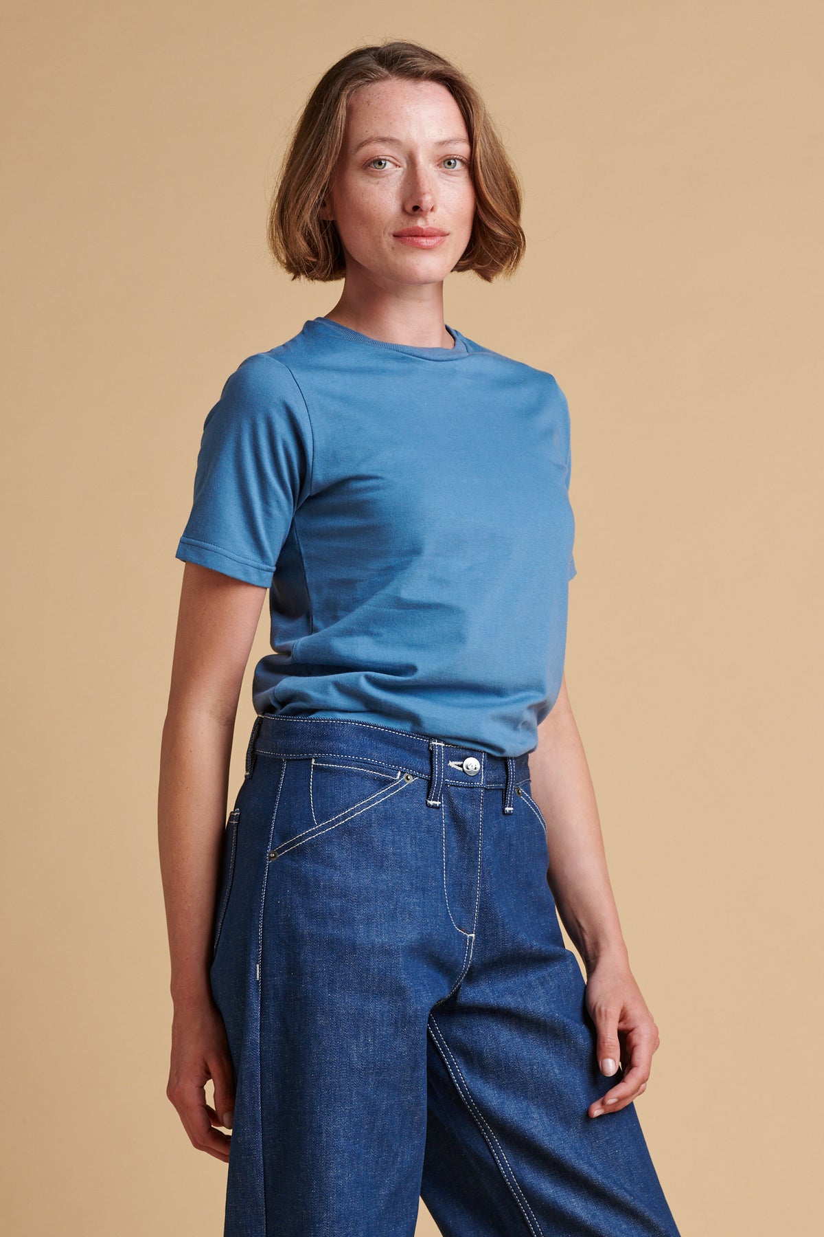 Thigh up front of female wearing short sleeve t shirt in RAF blue.