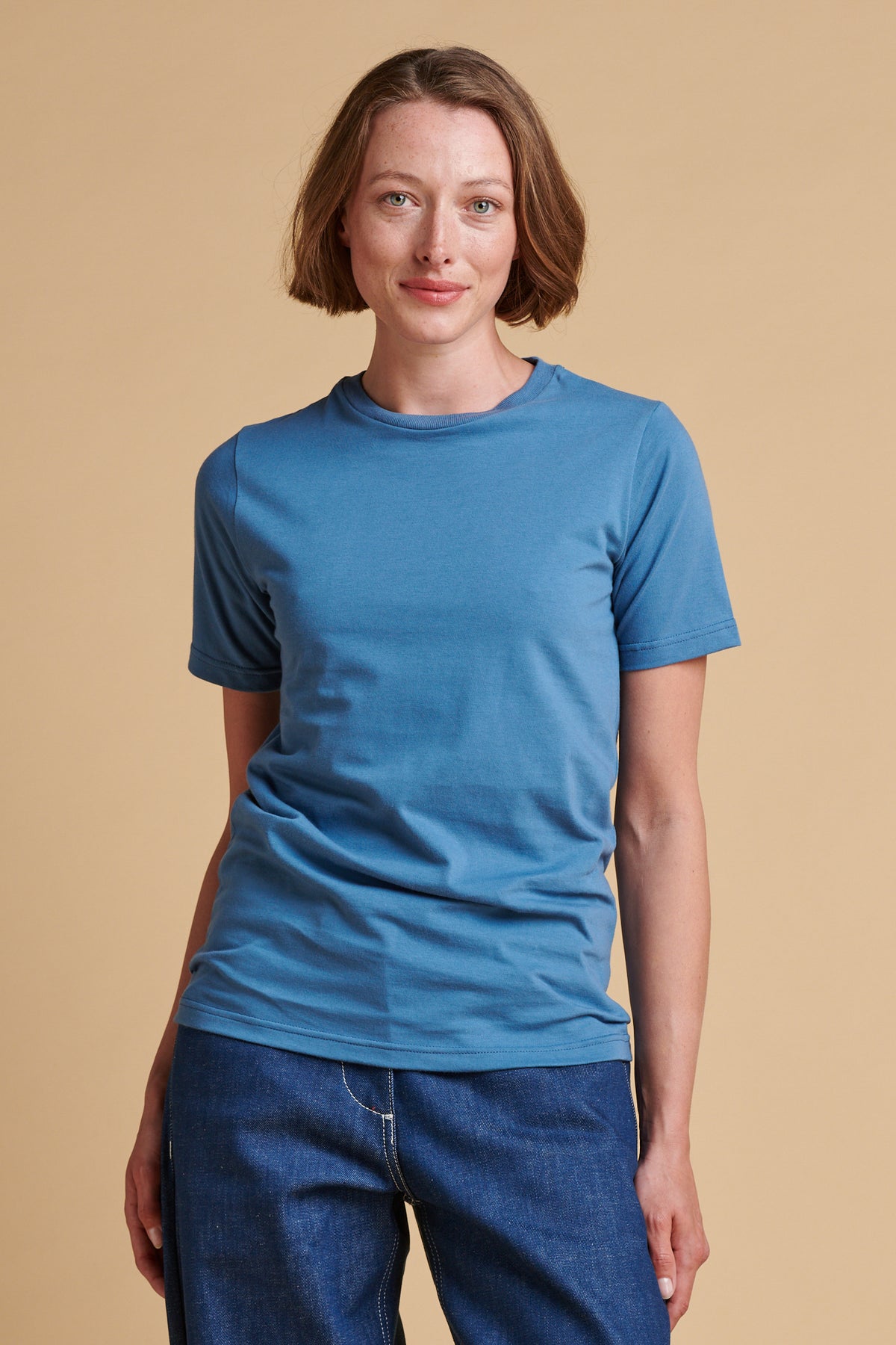 Thigh up front of female wearing short sleeve t shirt in RAF blue.