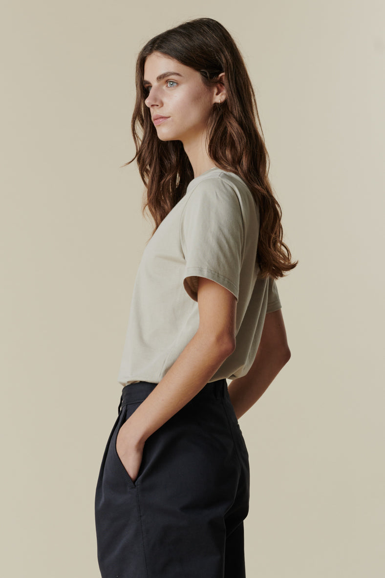 
            Thigh up image of female wearing short sleeve t shirt in stone paired with pleated trousers in navy