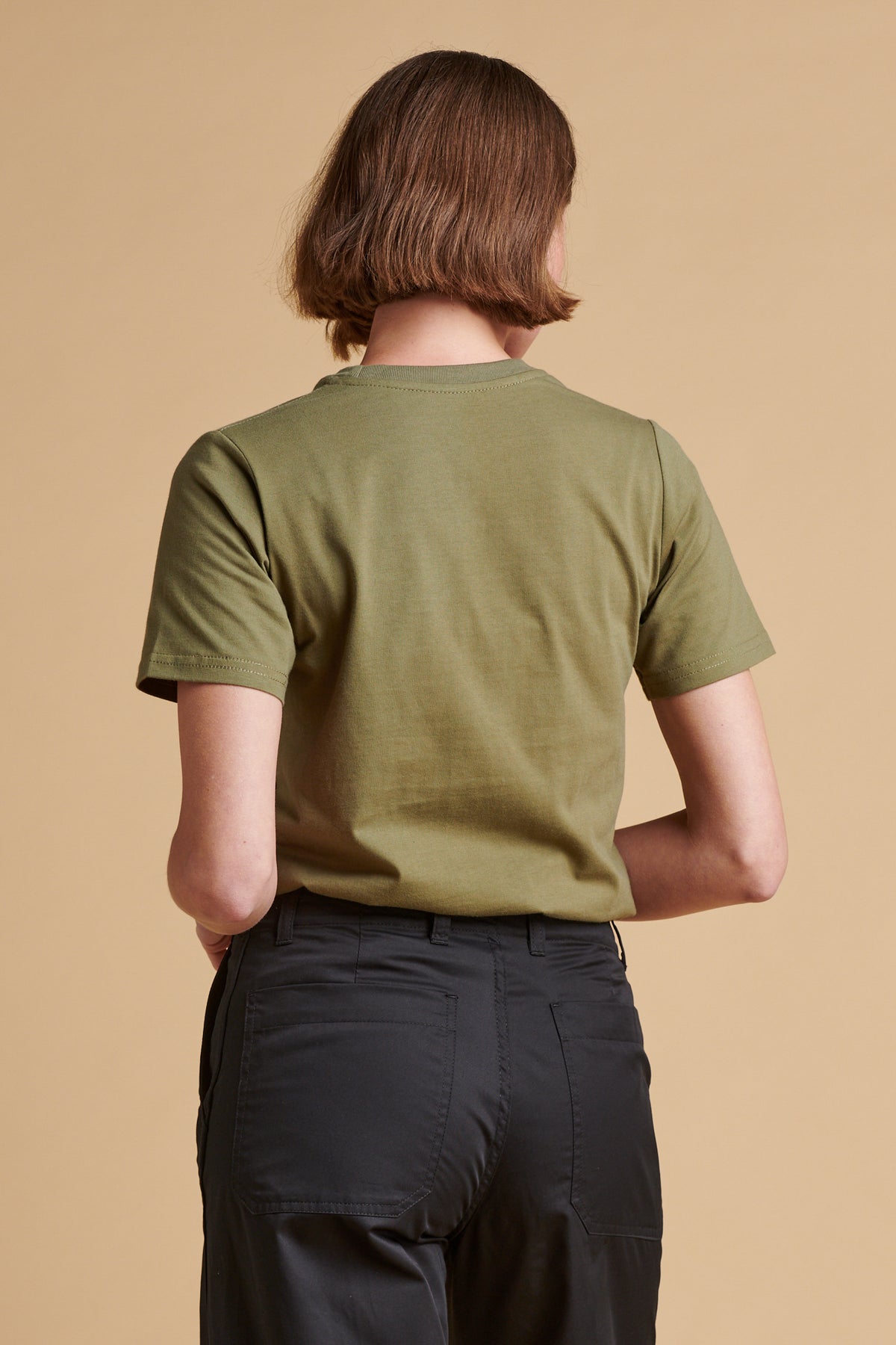 The back of female wearing short sleeve t shirt in olive.