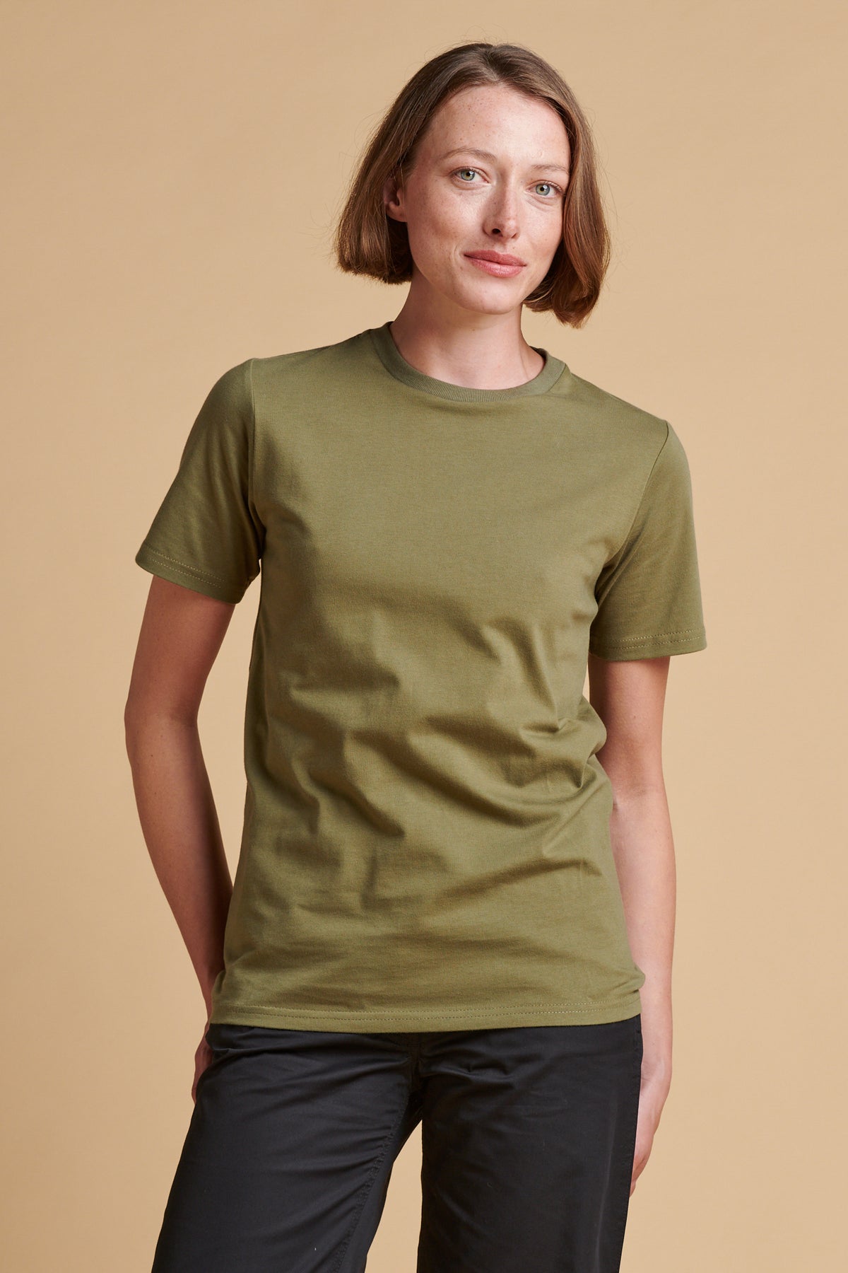 Thigh up front of female wearing short sleeve t shirt in olive.