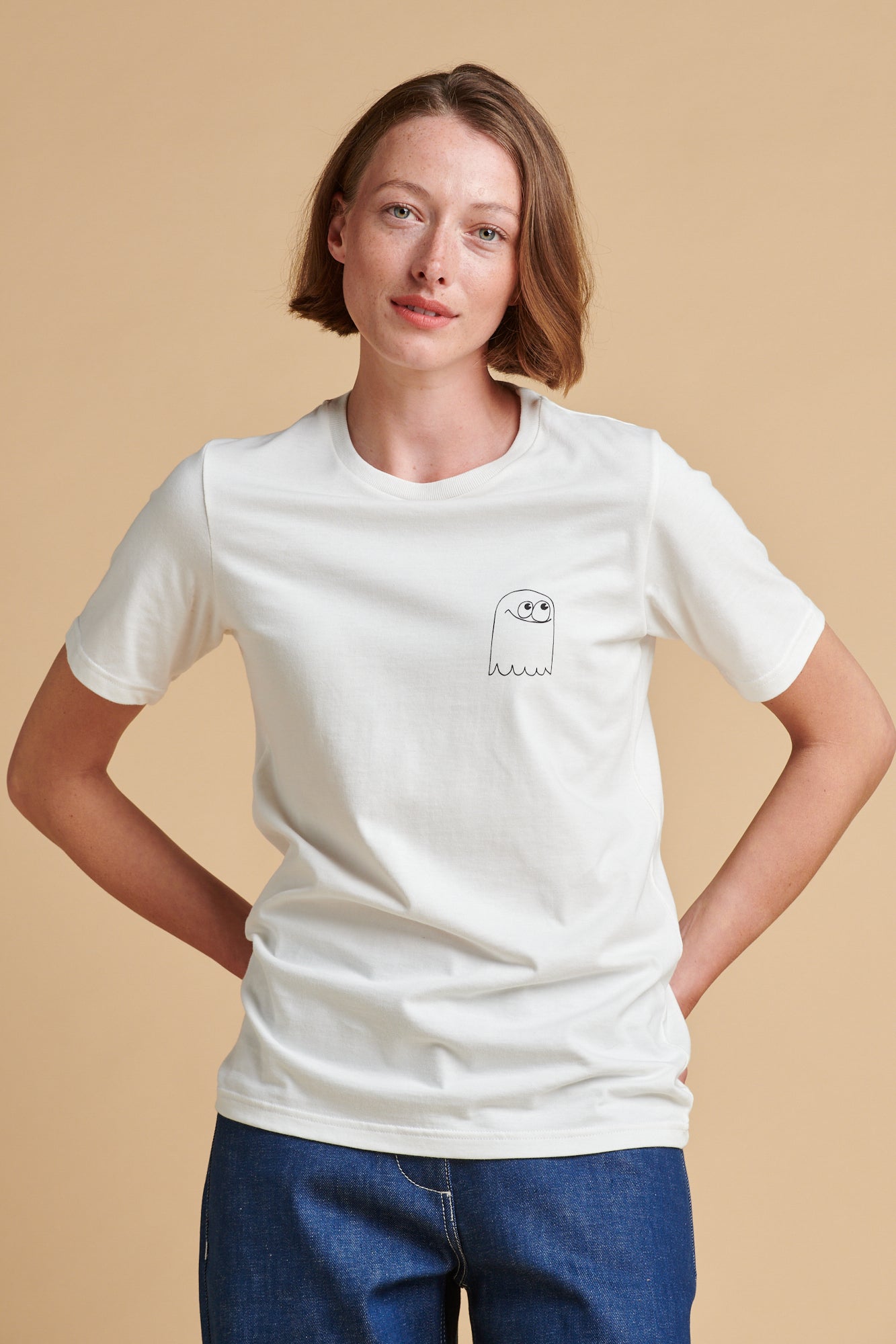 Person wearing a white t-shirt with a small graphic on a beige background