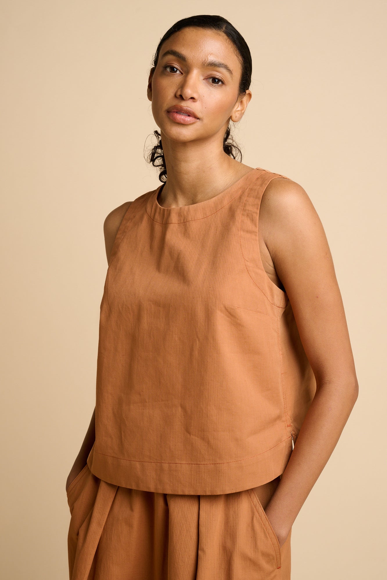 Woman wearing sleeveless orange top.