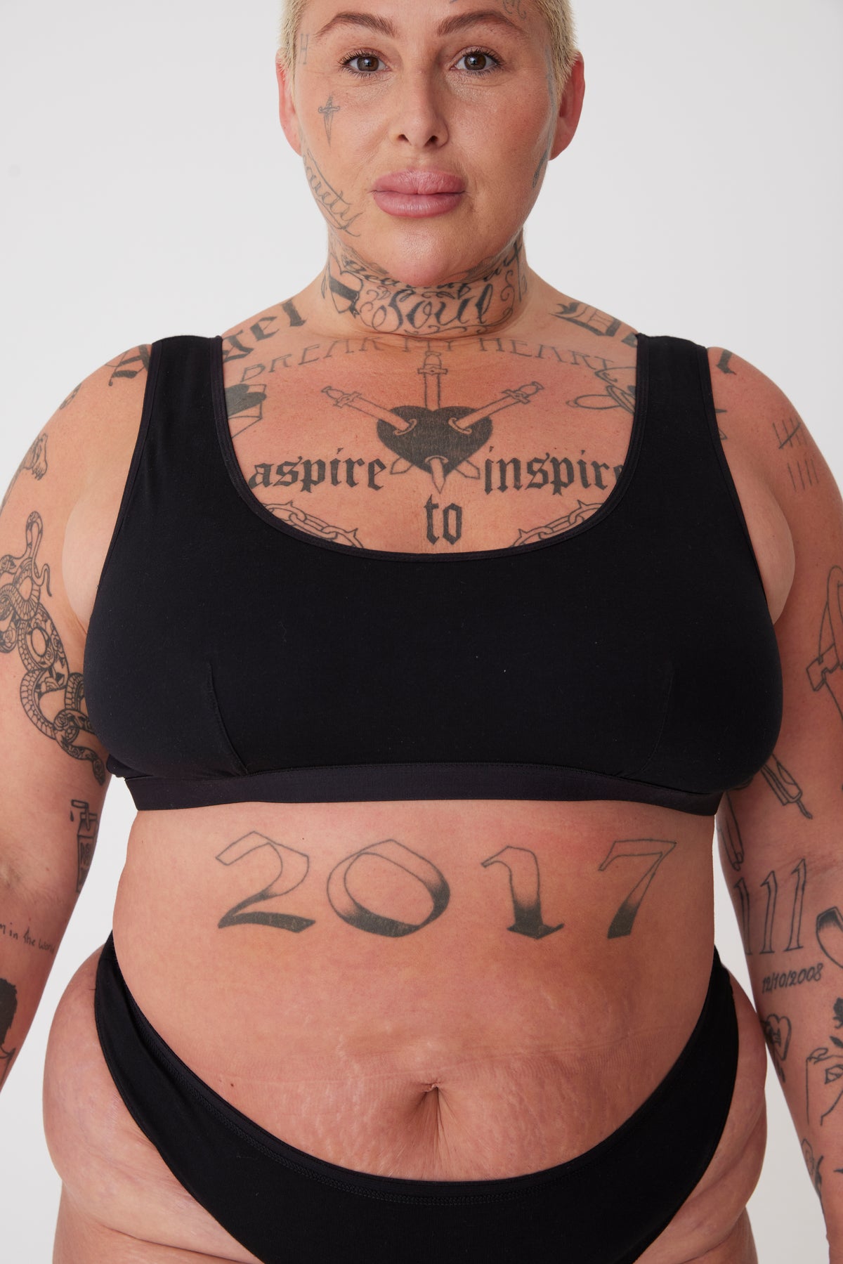 Plus sized white female with cropped blonde hair wearing a black soft jersey bra and black knickers from community clothing