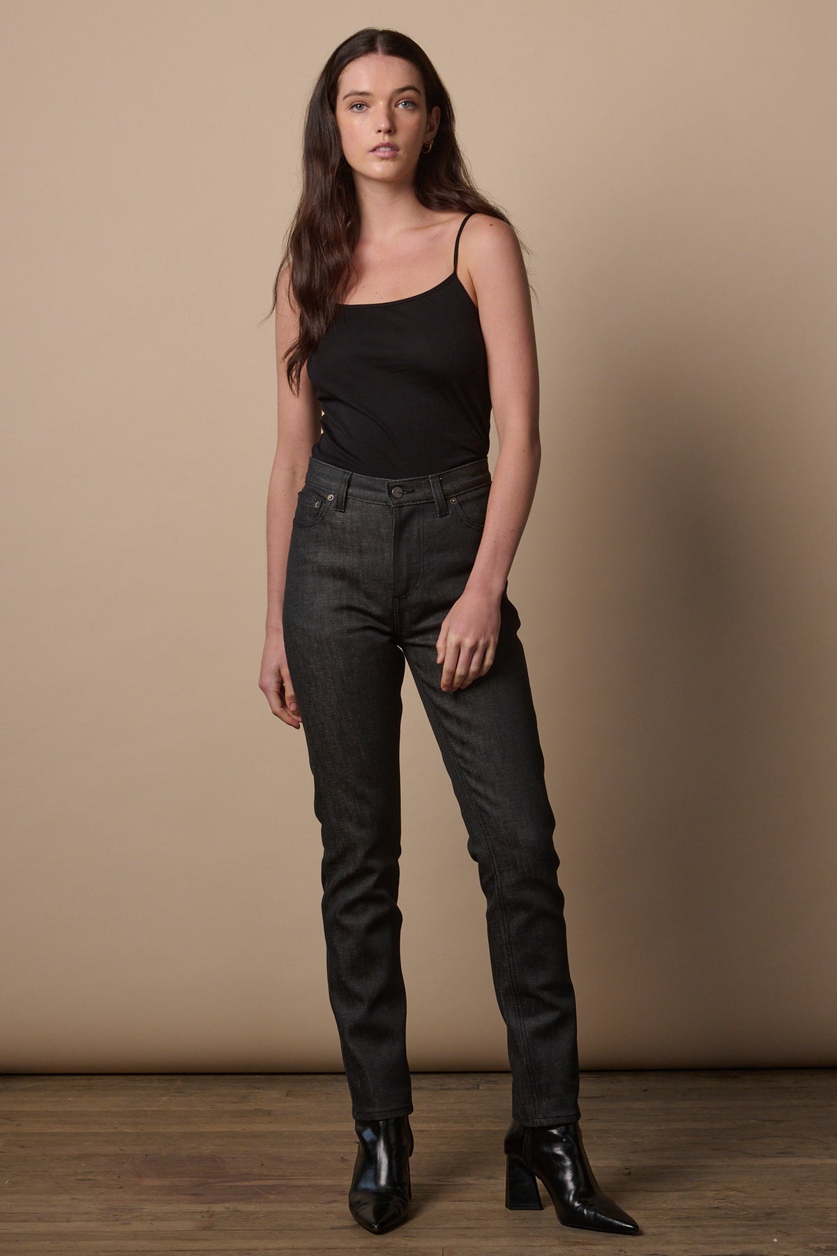 Full body image of female wearing high waist jeans in black with black camisole tucked in