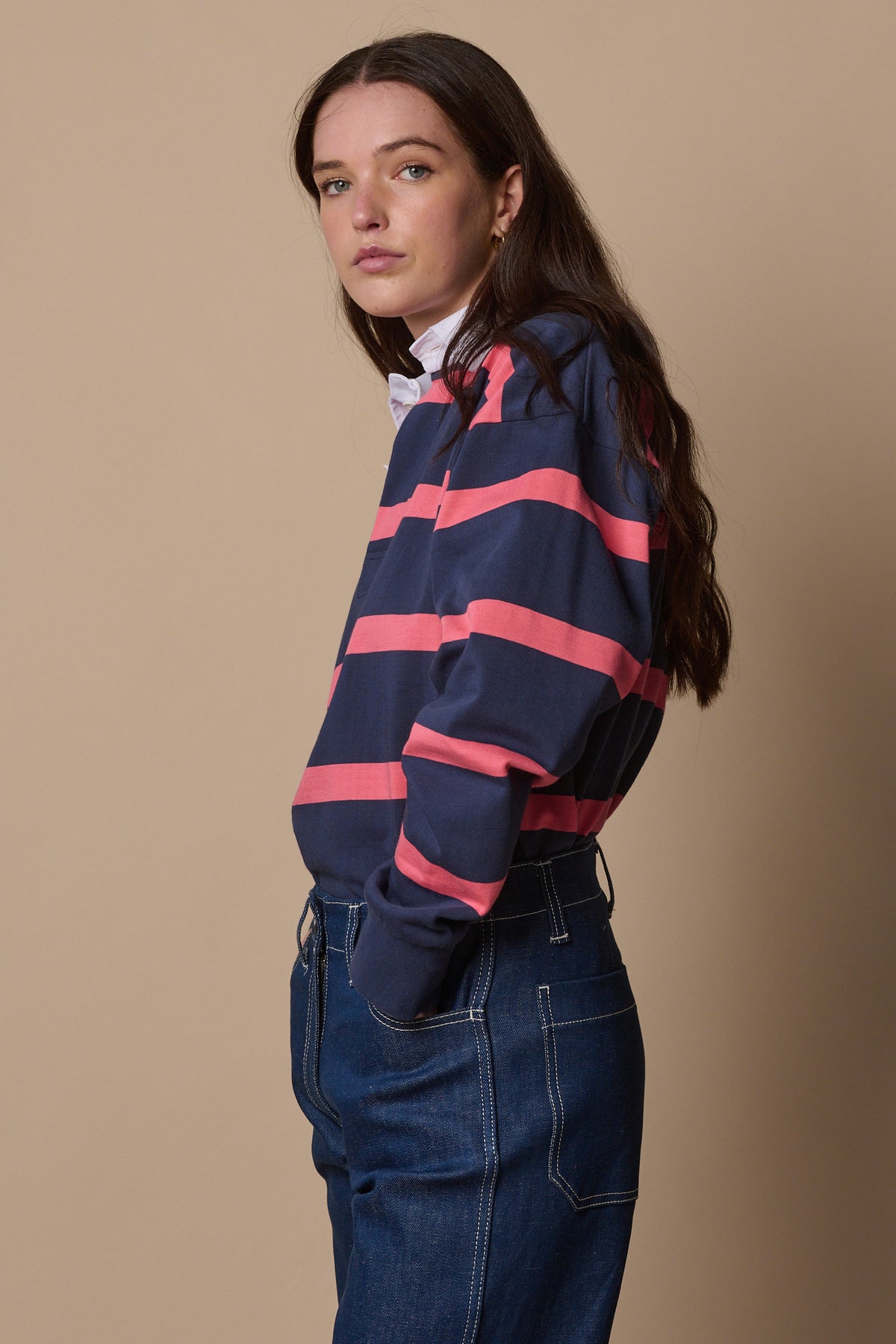 
            Image of the side of female wearing stripe rugby shirt in navy from the side with hand in jean pocket