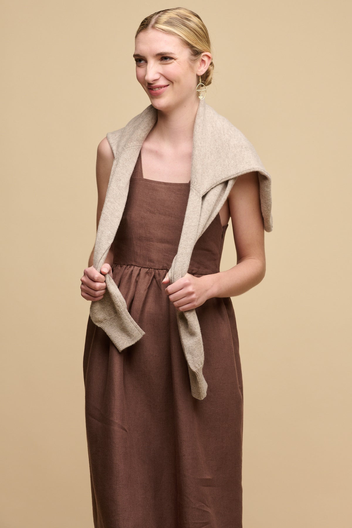 
            Image of the front of smiley female wearing sun dress in cocoa with lambswool crew neck draped over shoulders