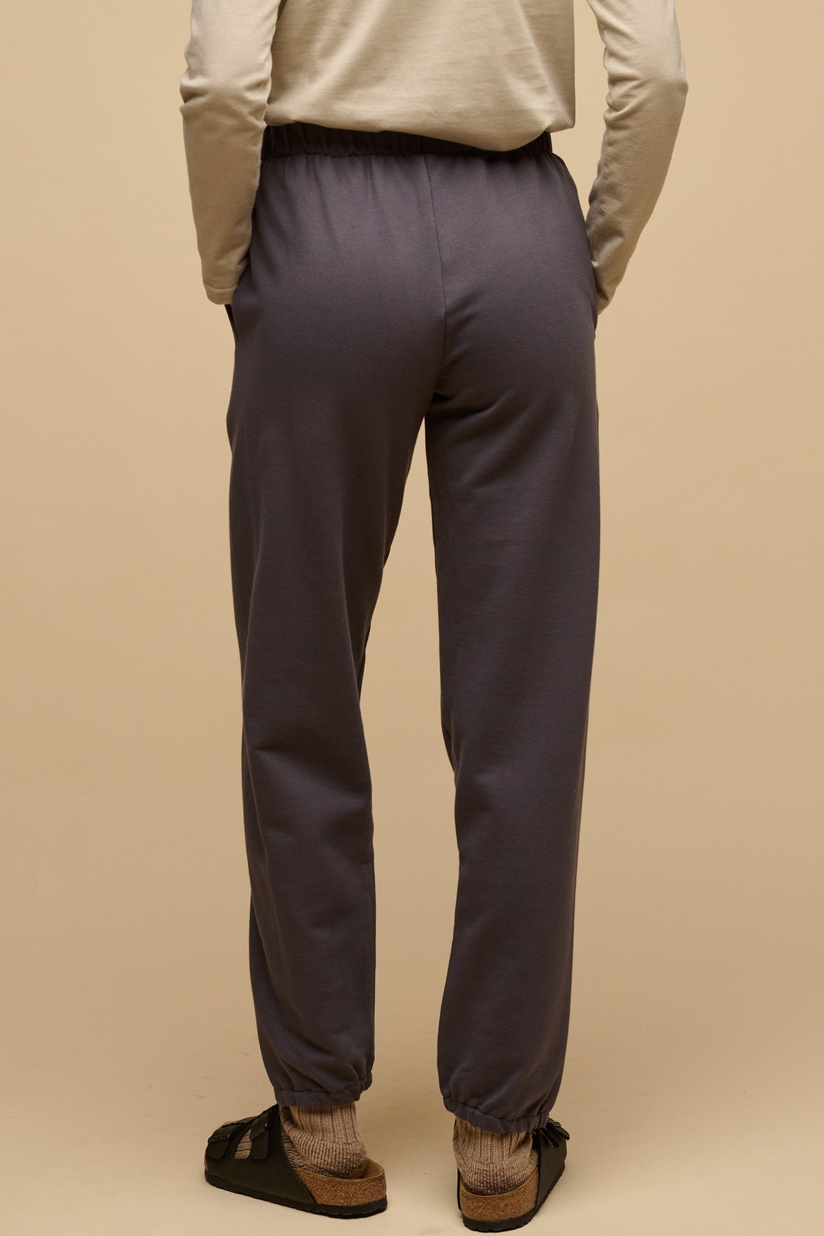 Waist down of the back of female wearing sweatpants in slate grey with hands in front pockets
