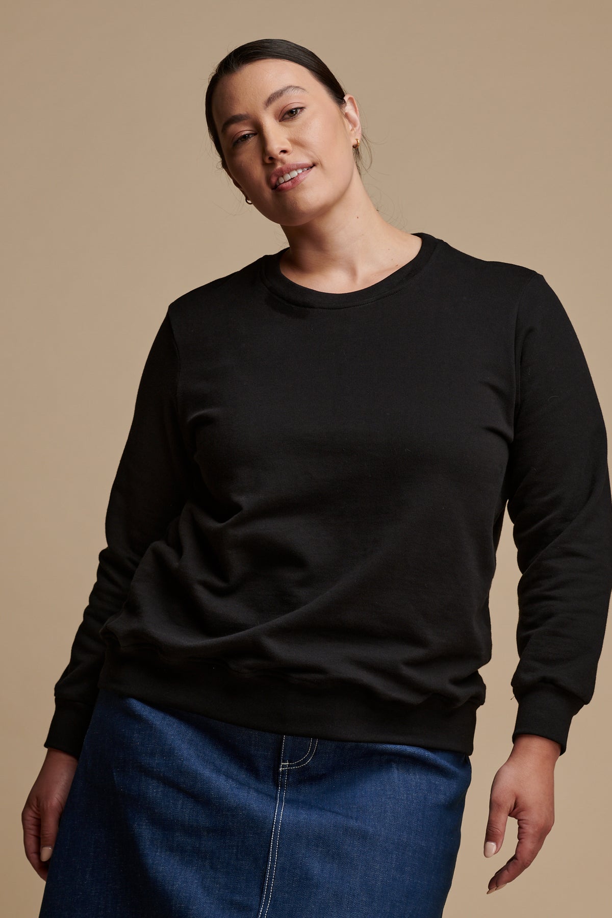 Thigh up of female wearing sweatshirt in black paired with bobbie skirt in blue.