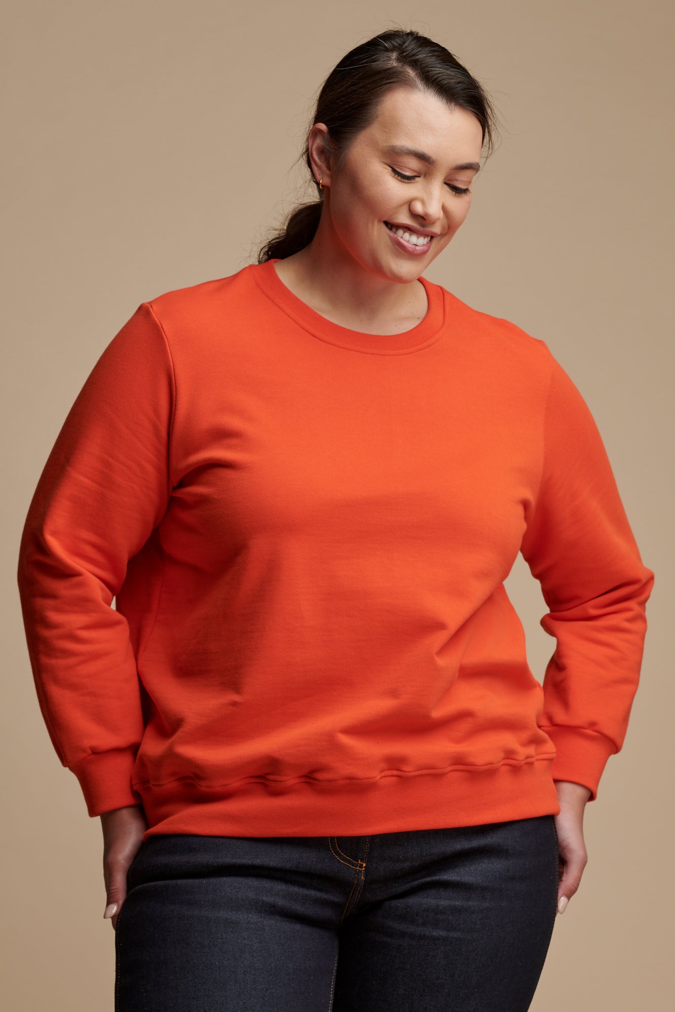 Smiley female looking towards the ground  wearing sweatshirt in flame red.