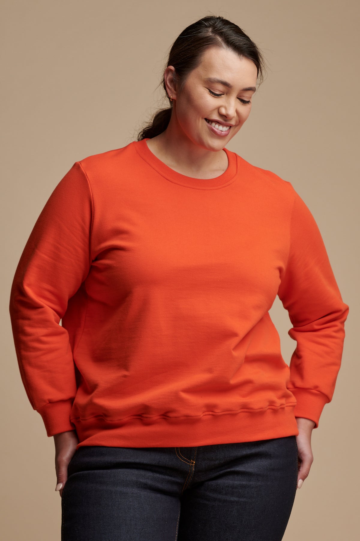Smiley female looking towards the ground wearing sweatshirt in flame red.