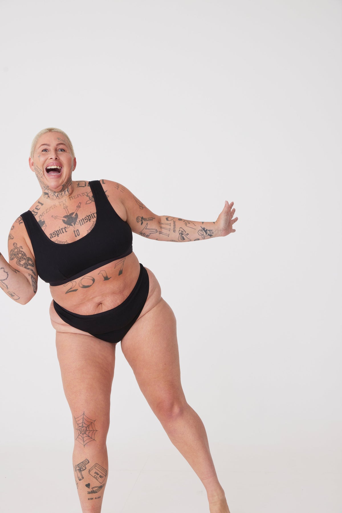 tattooed, plus size, white female front full body wearing black thong paired with black soft jersey bra