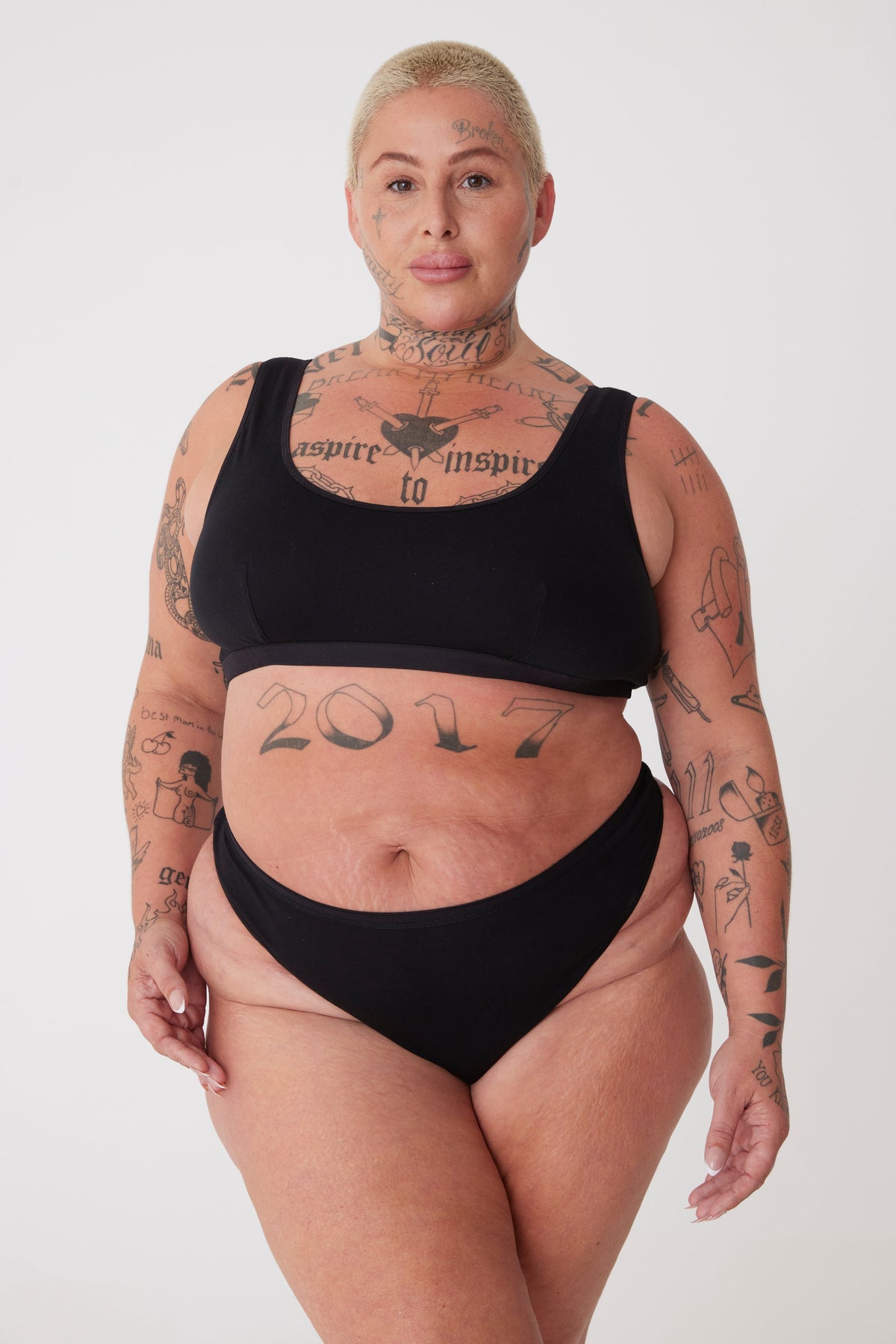 tattooed, plus size, white female thigh up wearing black thong paired with black soft jersey bra
