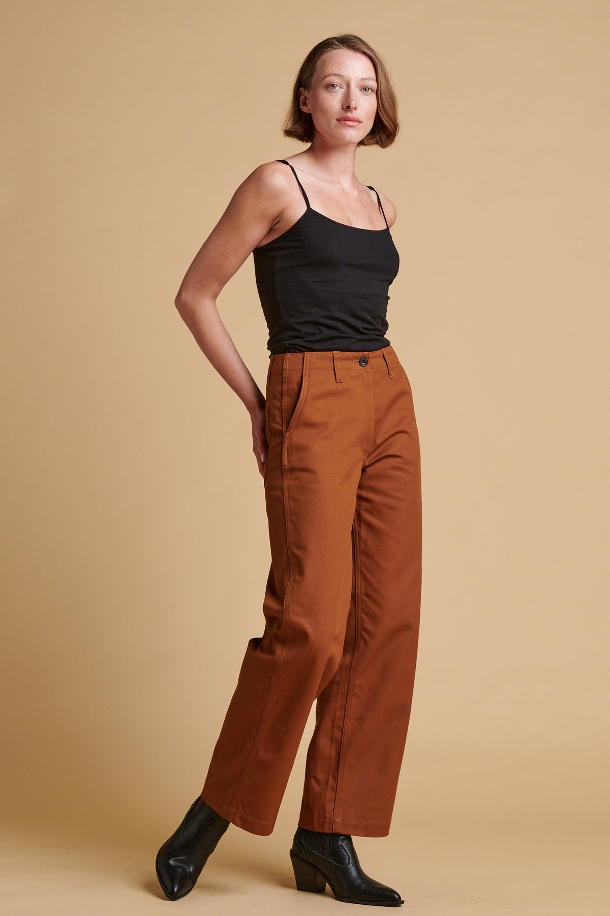 Female wearing twill work trousers in dark tan paired with black camisole.