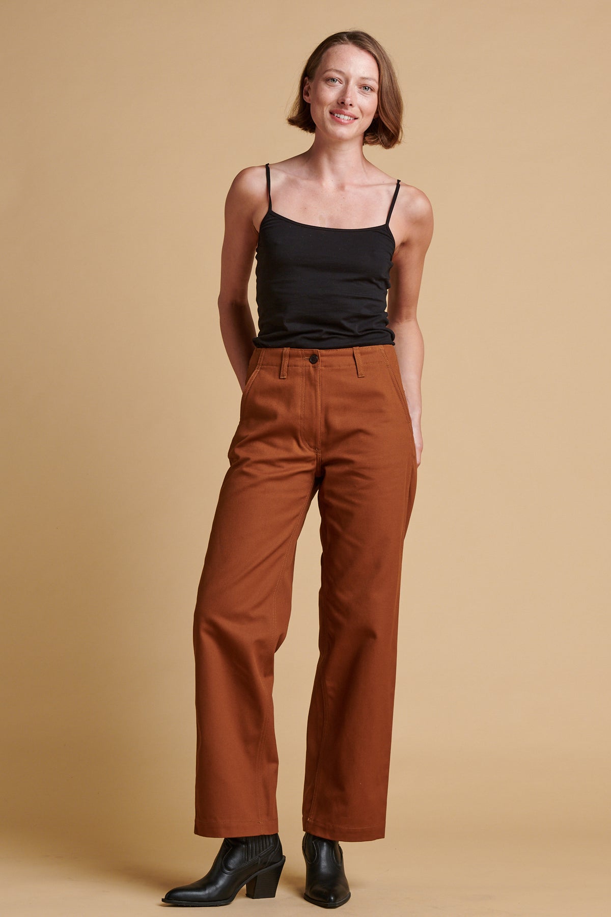 Female wearing twill work trousers in dark tan paired with black camisole.