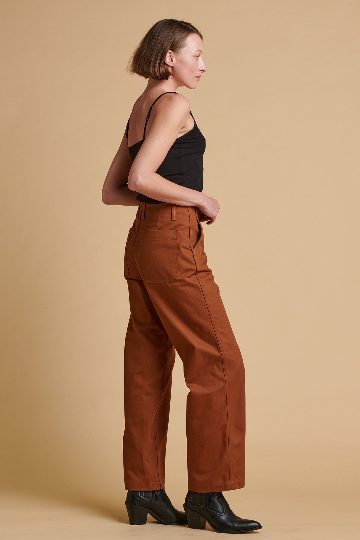 Female wearing twill work trousers in dark tan paired with black camisole.