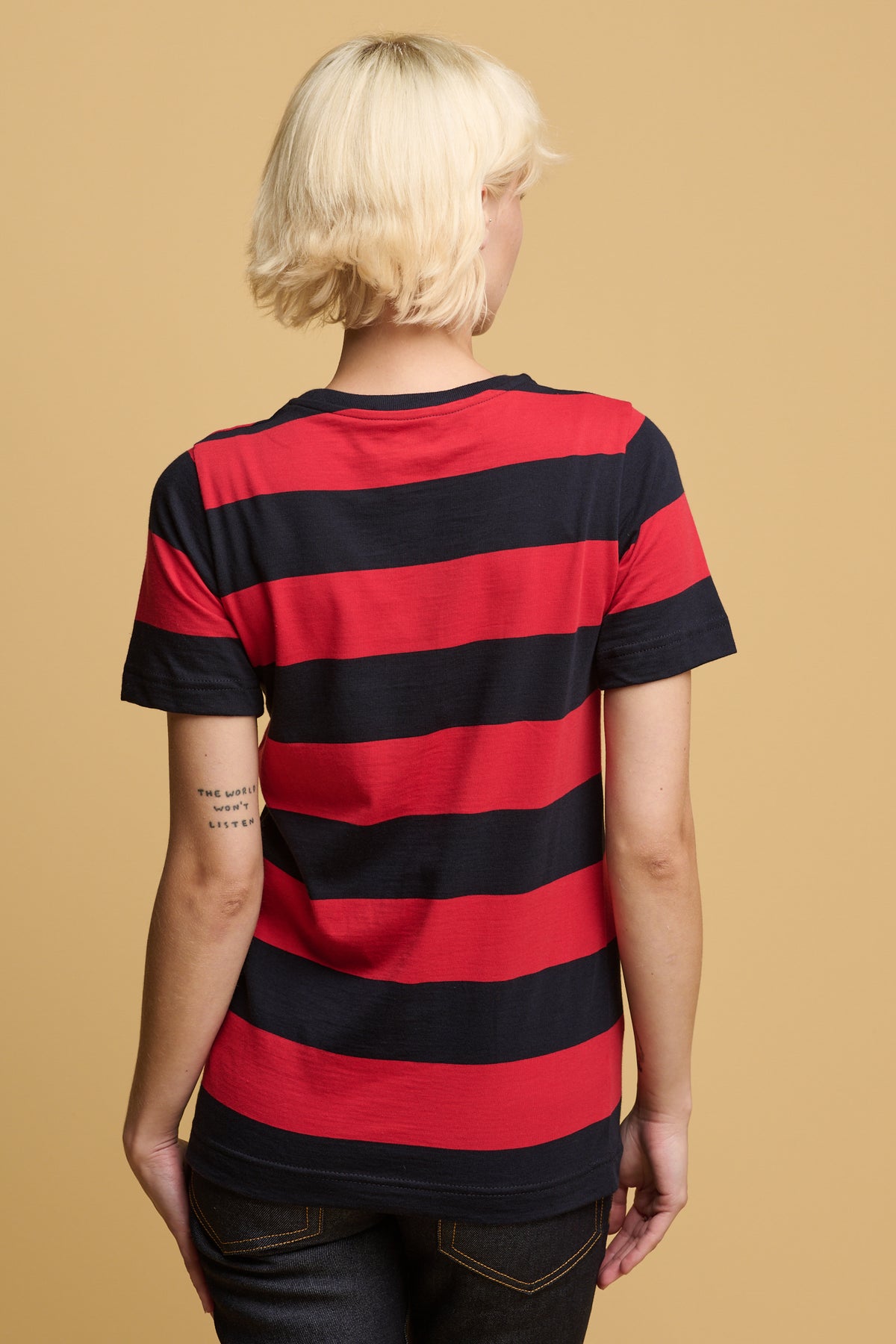 Thigh up image of the back of female wearing wide stripe short sleeve t shirt in red and navy