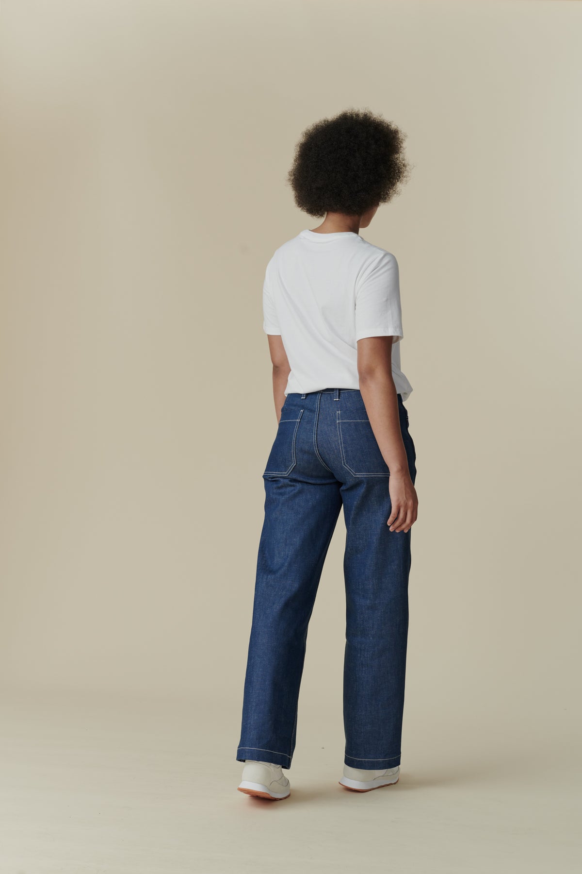 
            Female with afro wearing white crew neck white t shirt paired with women&#39;s work jean in Blue, white contrast stitching