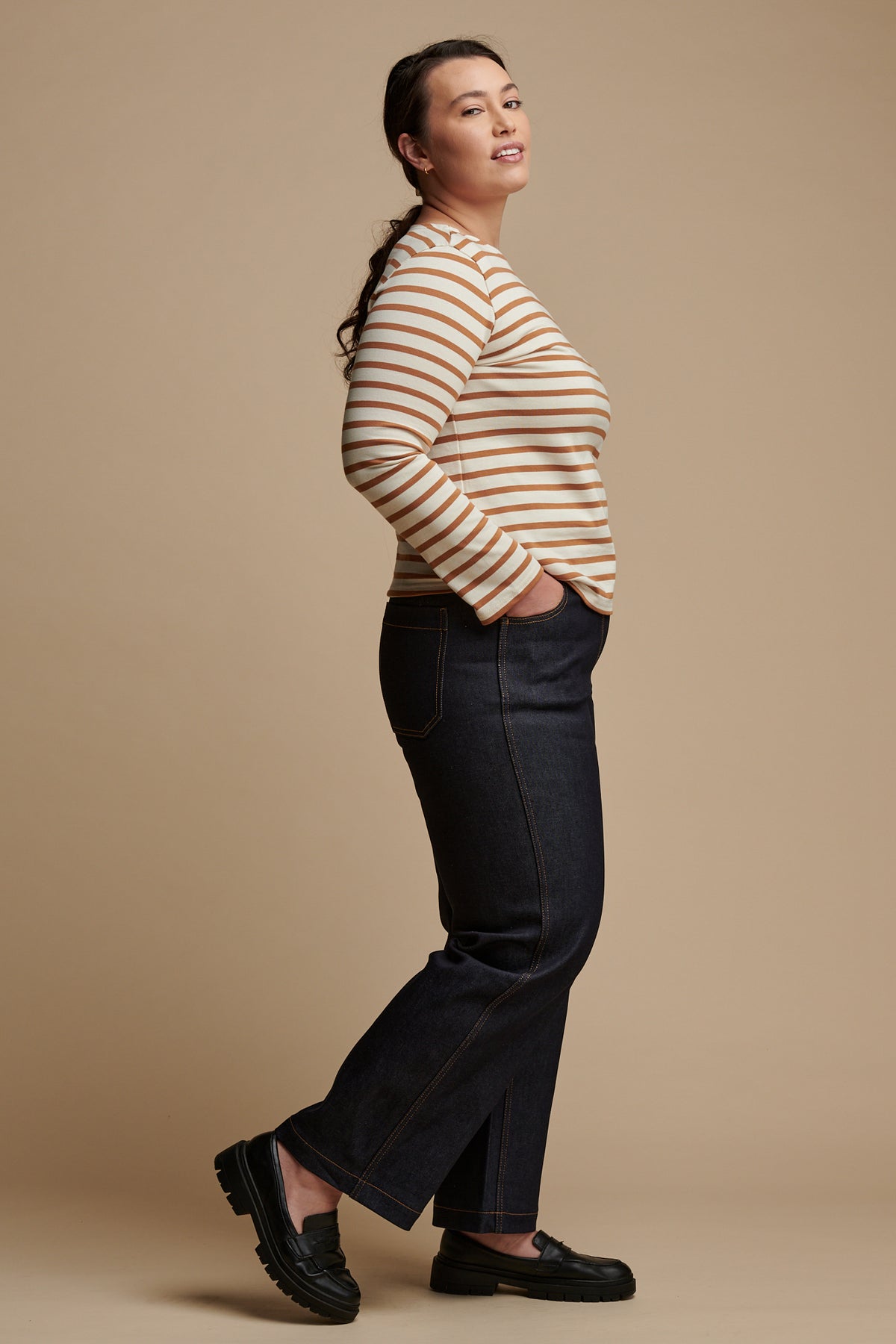 The side of female wearing work wide straight jean in indigo paired with Breton top in ecru-cinnamon.