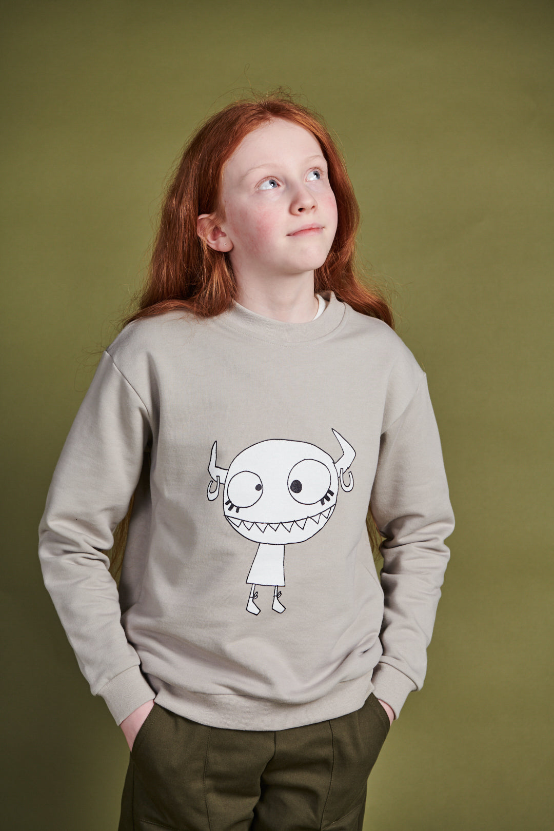 Girl wearing plastic free sweatshirt in stone with Grunhilda print on front
