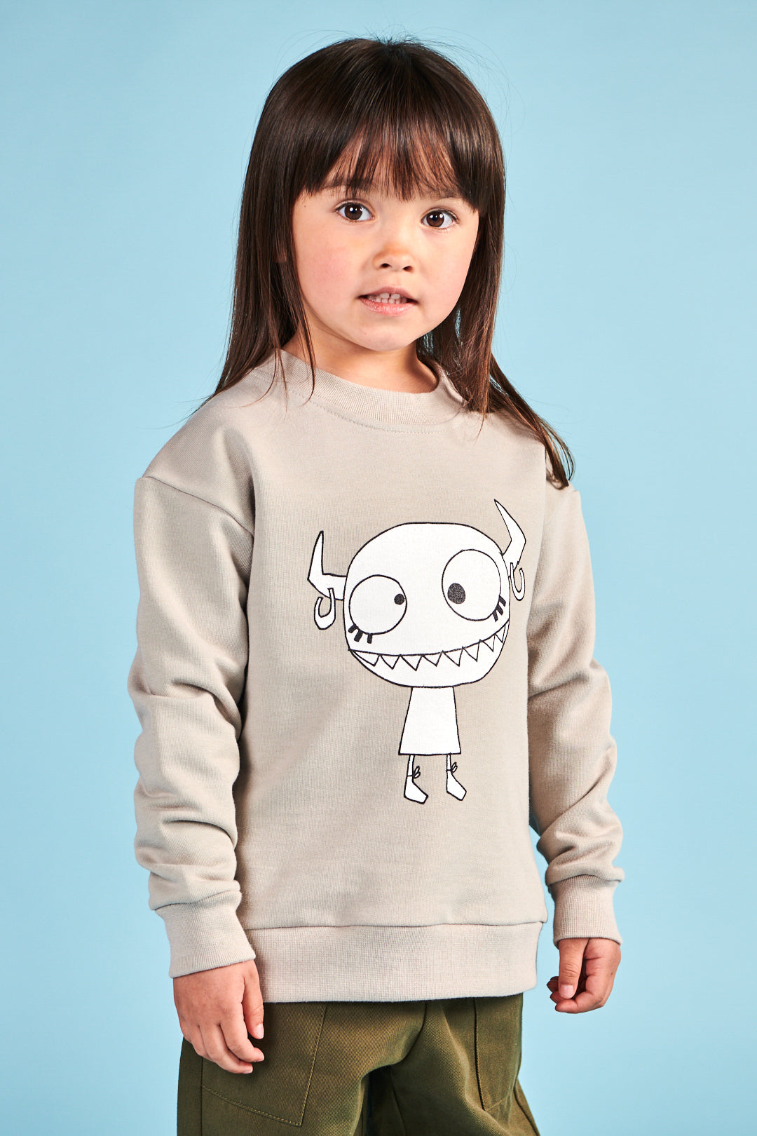 Girl wearing plastic free sweatshirt in stone with Grunhilda print on front