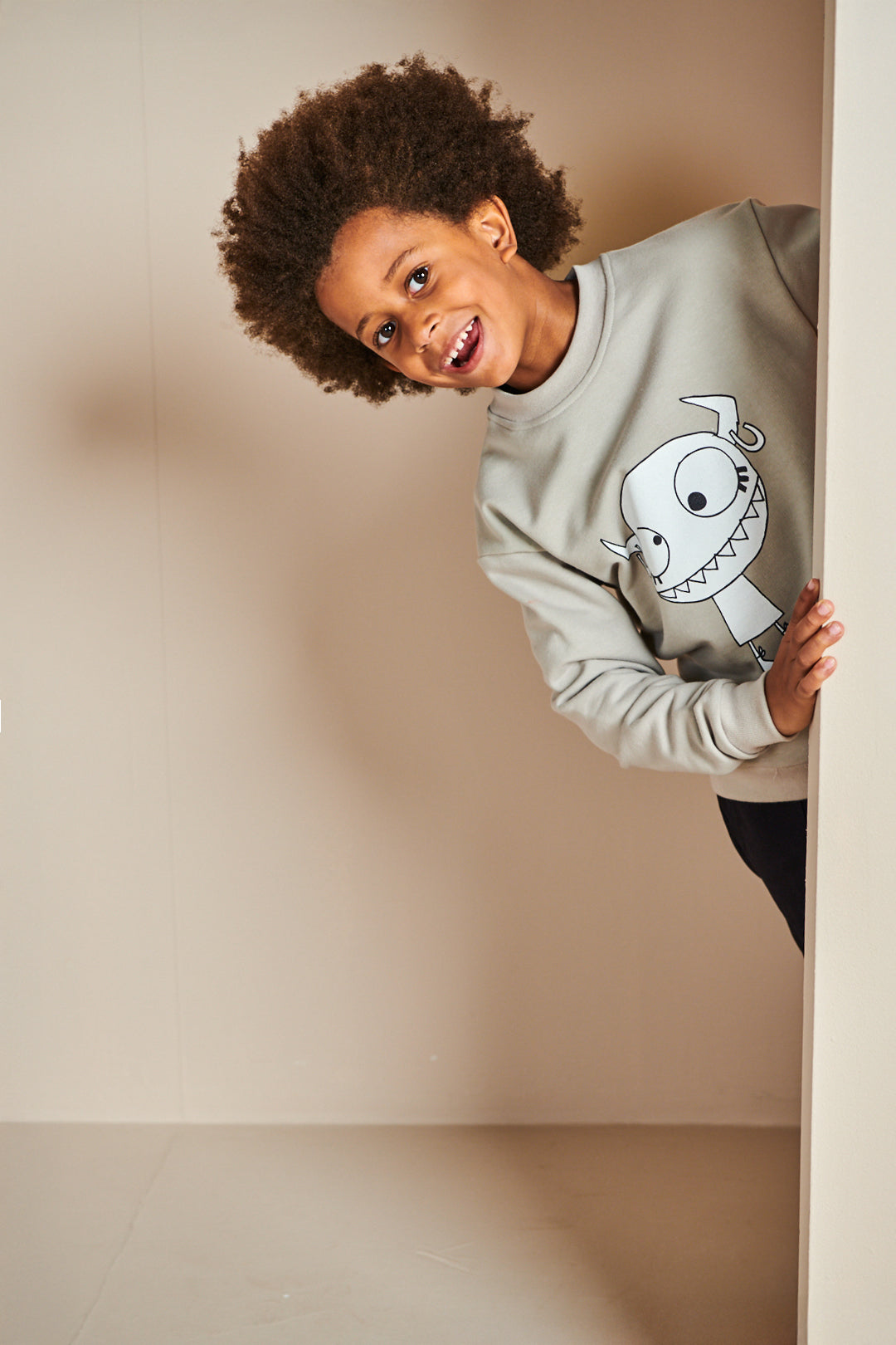 Boy wearing plastic free sweatshirt in stone with Grunhilda print on front
