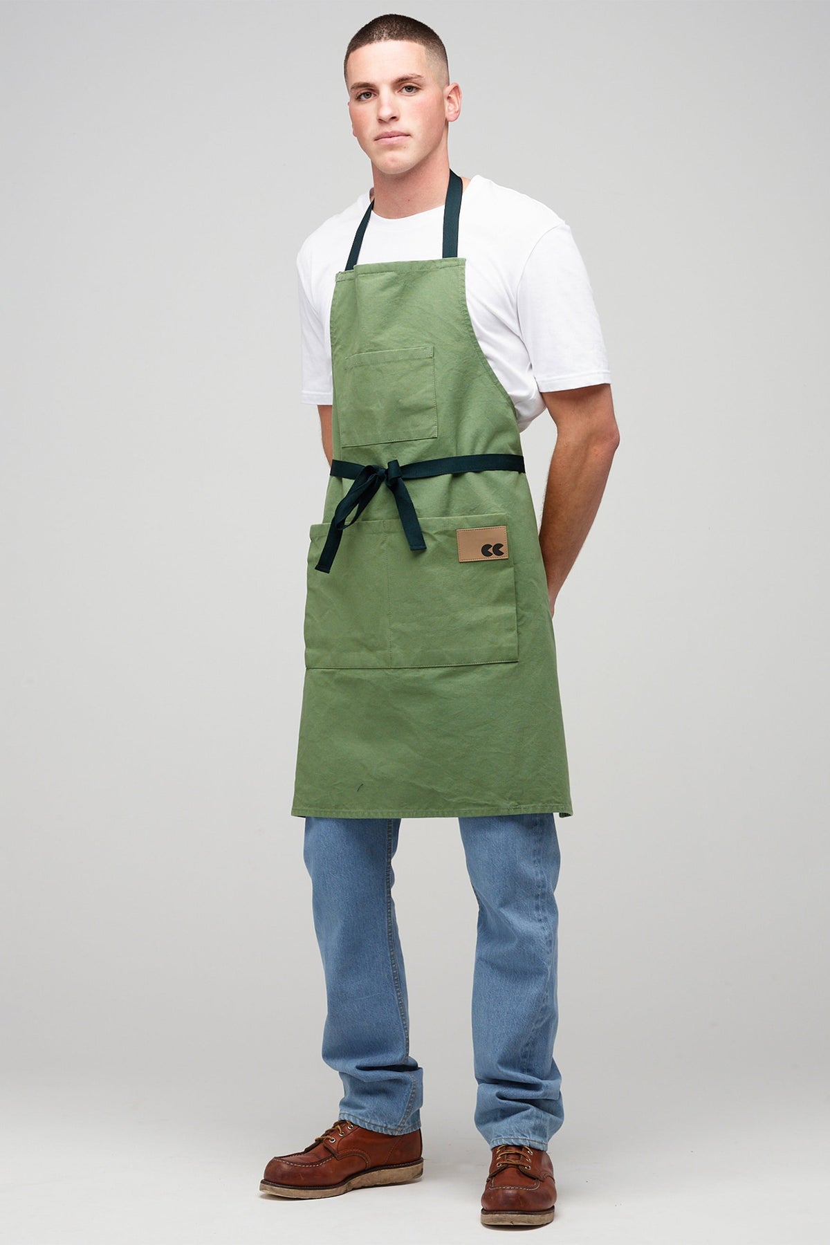 A young, white male with buzzcut hairstyle wearing a sage Apron.
