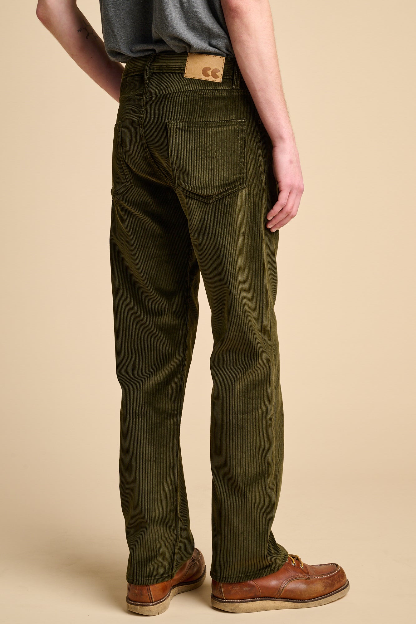 The back of a man wearing dark olive corduroy jeans with brown boots.