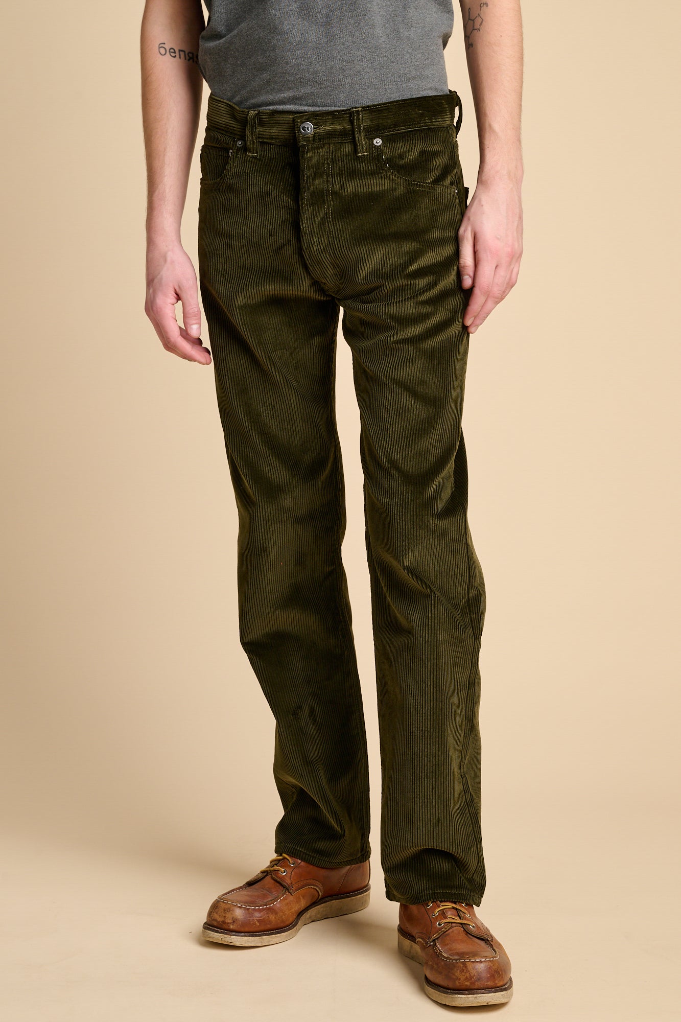 A man wearing dark olive corduroy jeans with brown boots.