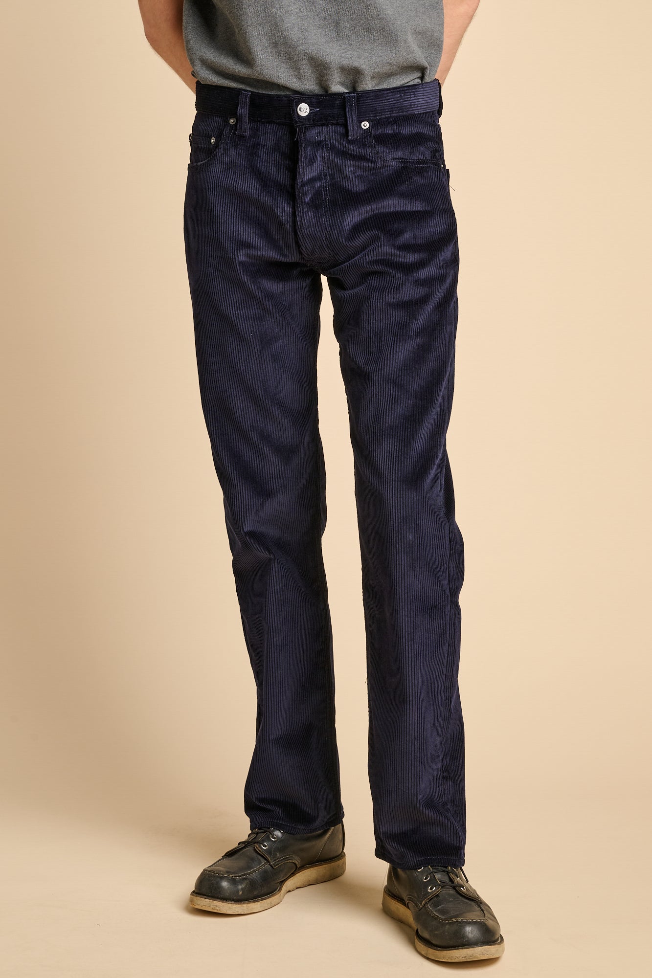 A man wearing navy corduroy straight leg jeans.