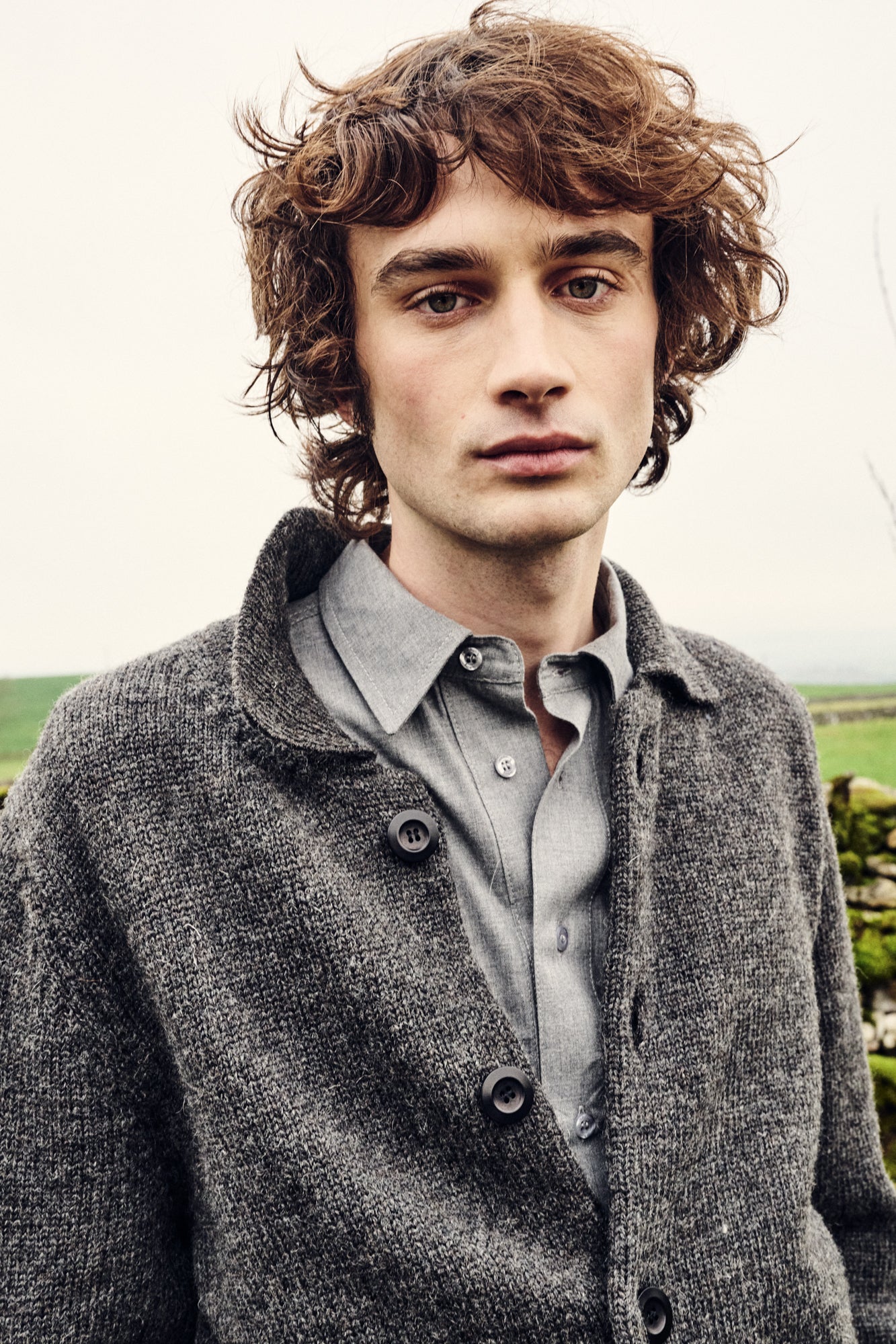 Man wearing charcoal marl knitted cardigan outside.