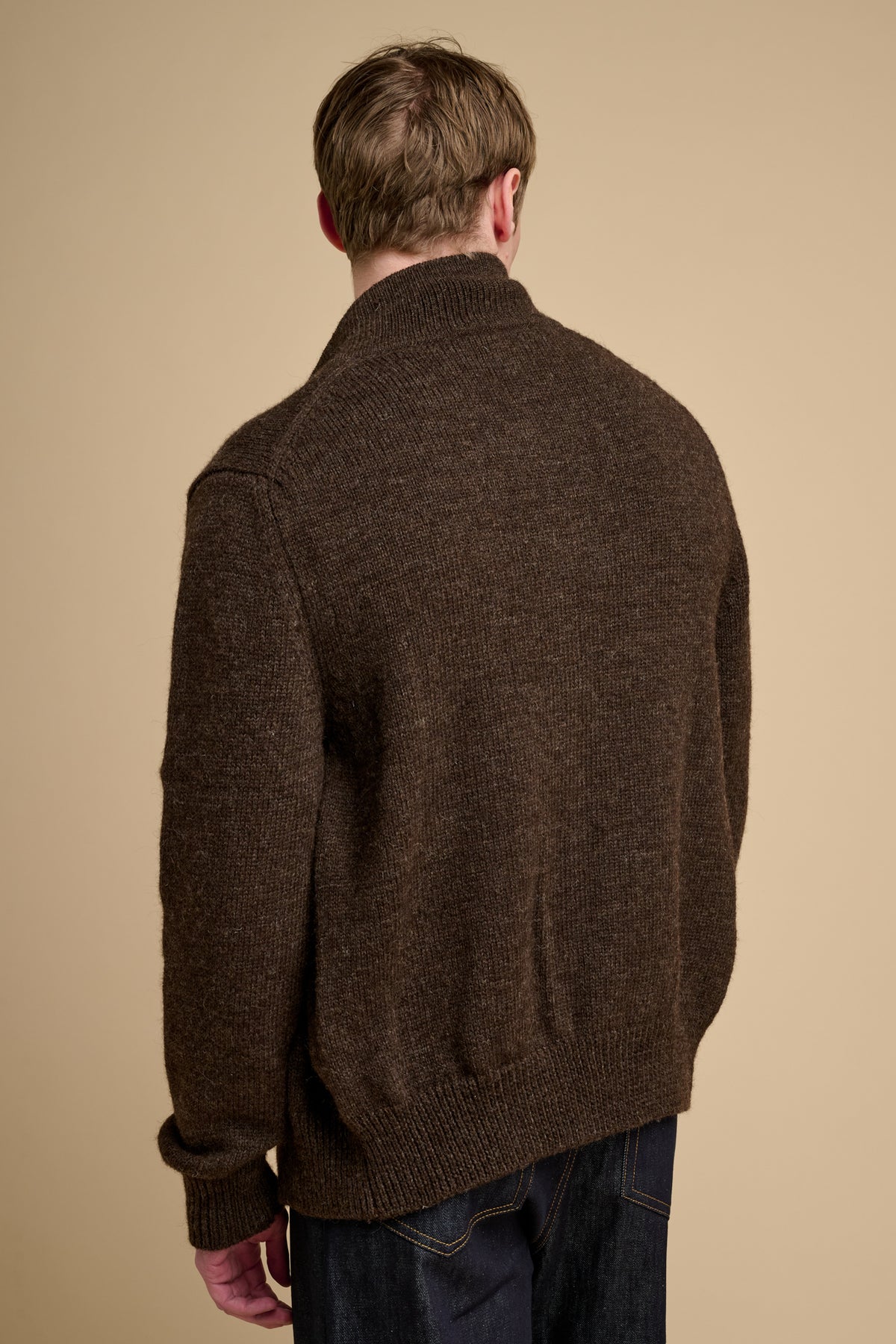Man wearing a brown knitted cardigan against a beige background