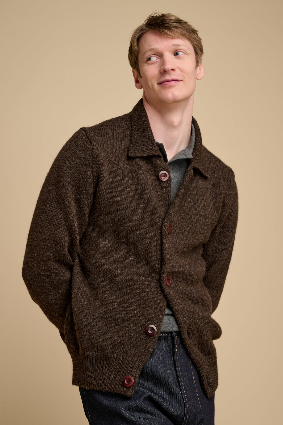 Man wearing a brown knitted cardigan against a beige background
