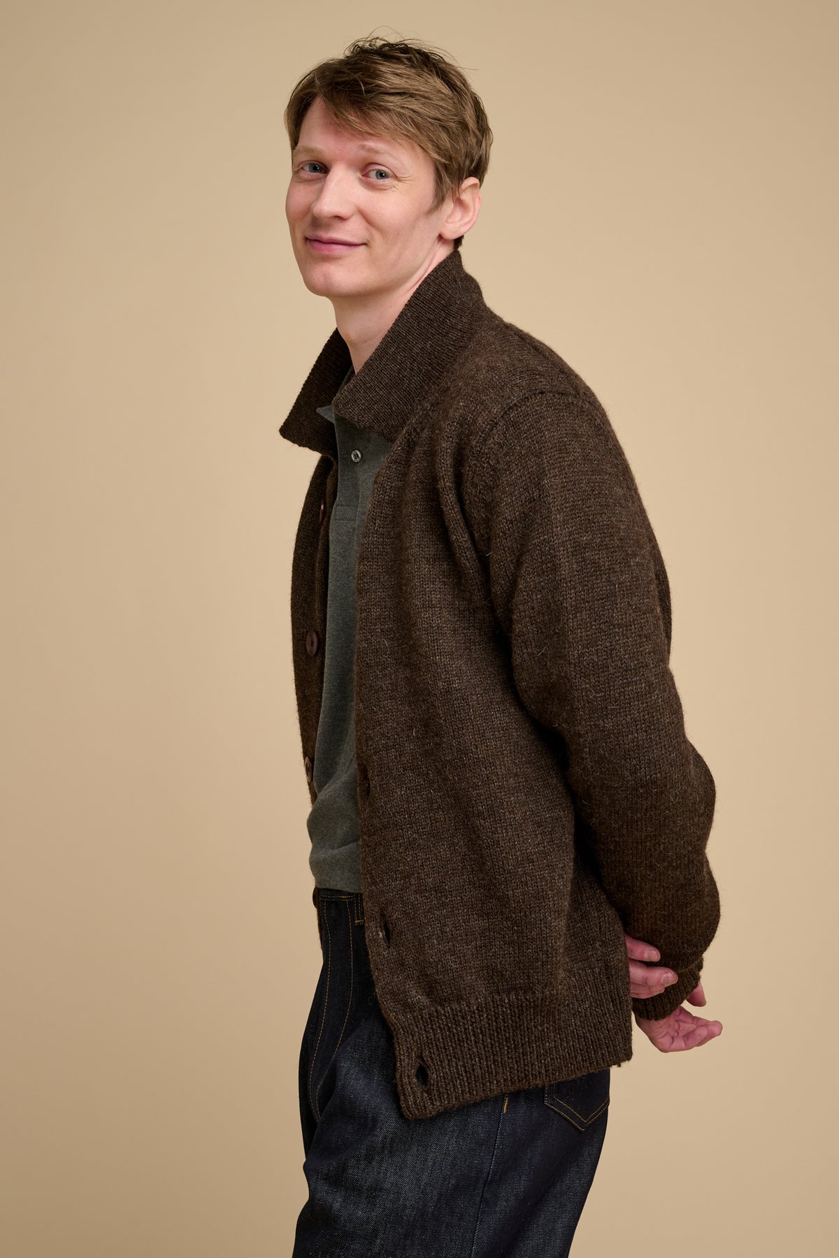 Man wearing a brown knitted cardigan against a beige background