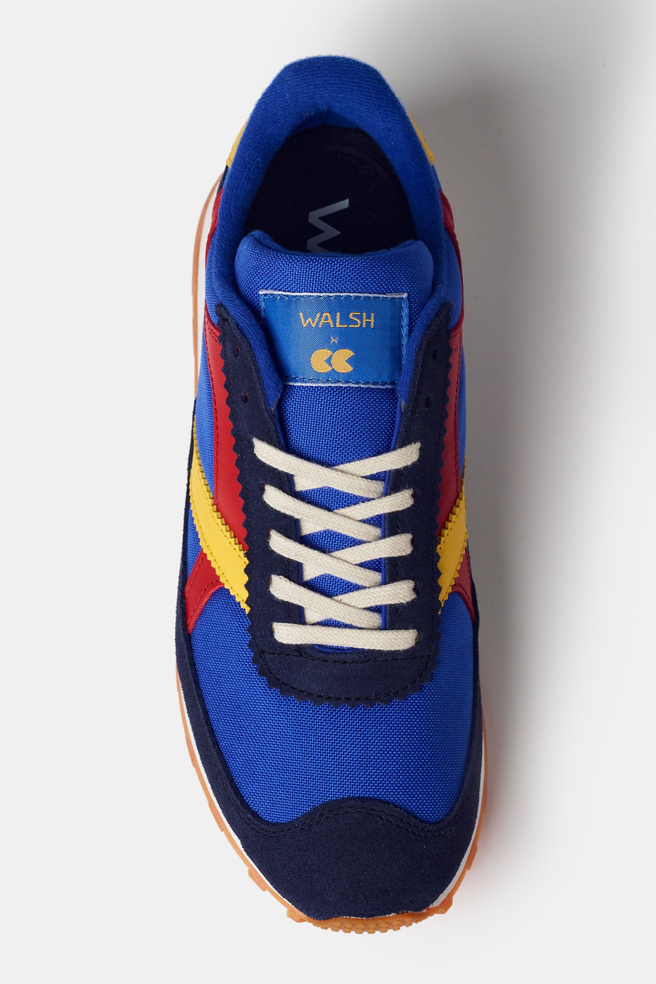Men's Beacon Trainer in blue. White laces with red and yellow side design. Walsh X CC tongue logo label 