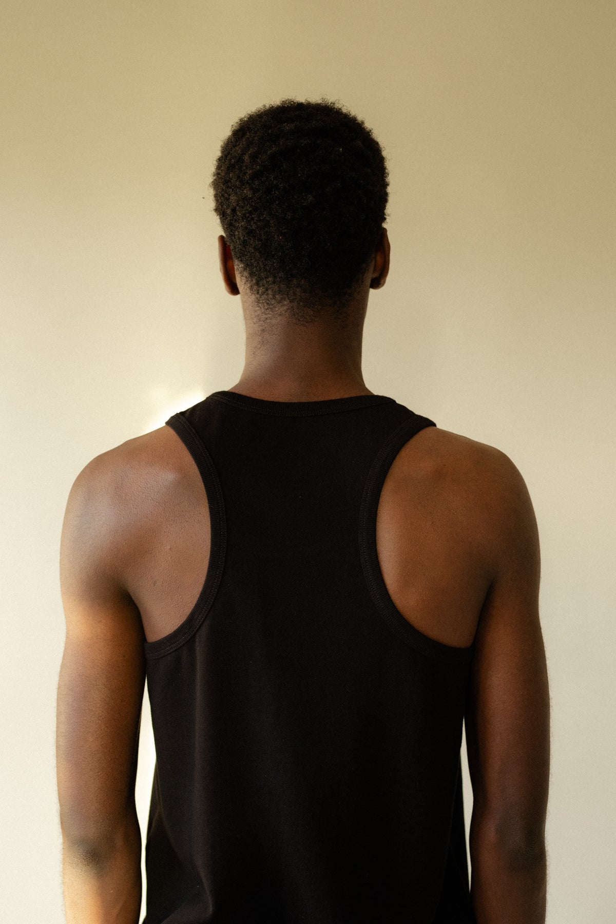 
            back of male wearing breathable racer back vest plastic free in black