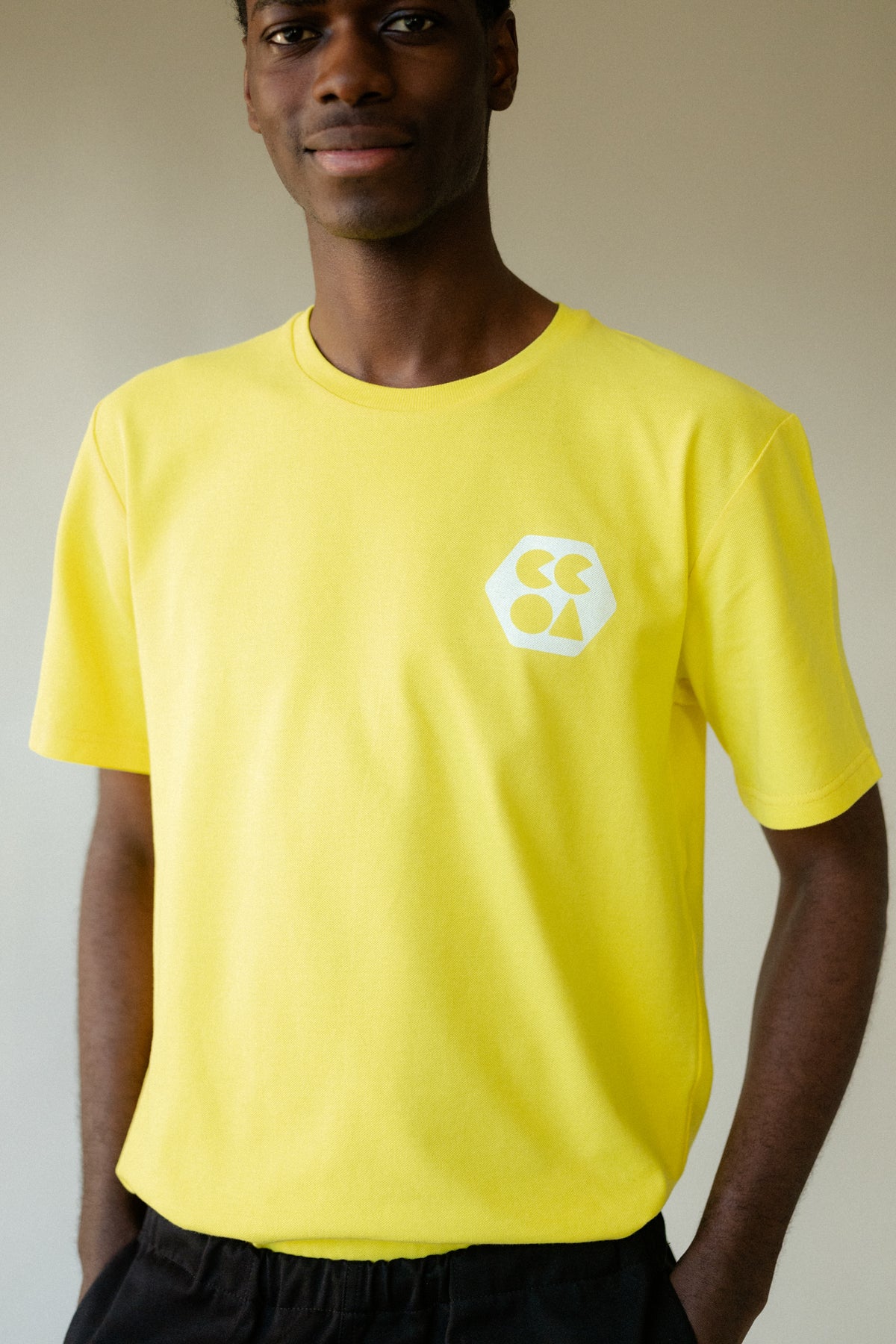 Male wearing men's breathable t-shirt plastic free in canary yellow with white CCOA logo