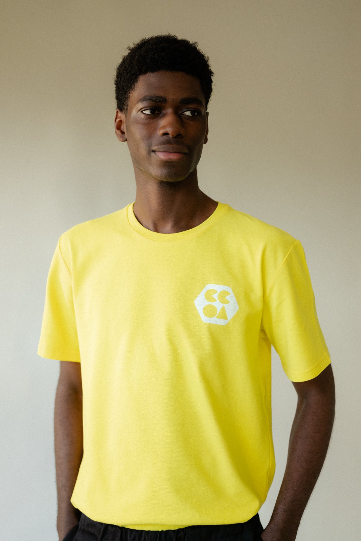 
            Male wearing men&#39;s breathable t-shirt plastic free in canary yellow with white CCOA logo