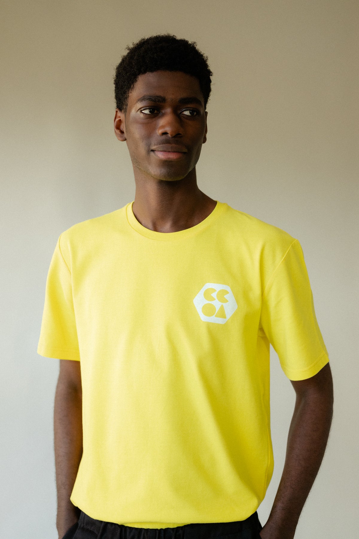 Male wearing men's breathable t-shirt plastic free in canary yellow with white CCOA logo