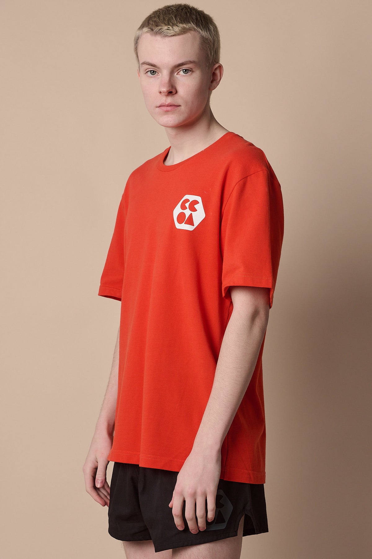 Thigh up image of white male wearing breathable t shirt plastic free in flame red with CCOA logo