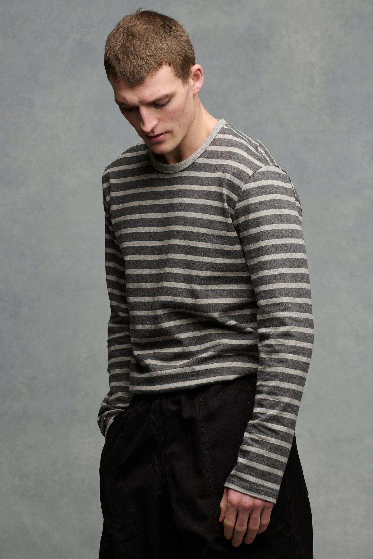 thigh up of the side of male wearing charcoal marl/grey marl Breton tucked into black cameraman pants