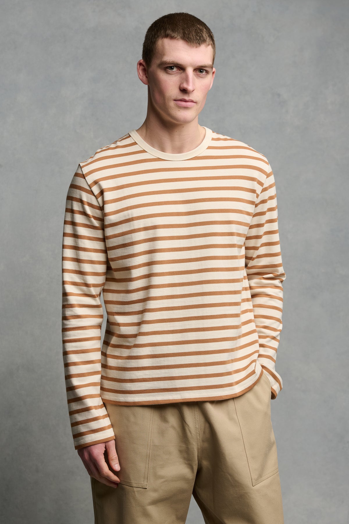 Male with short brown hair wearing Breton in ecru cinnamon paired with cameraman pants in putty