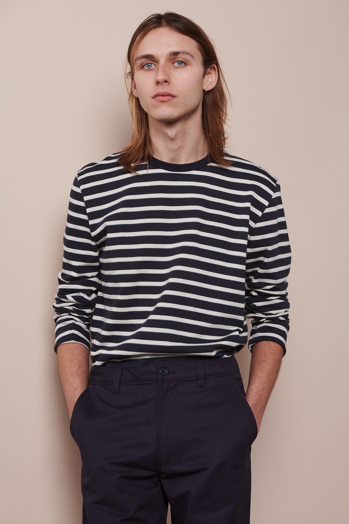 
            Thigh up image of male wearing Breton navy ecru with arms pushed up the arm slightly with hands in the front pockets of navy chinos