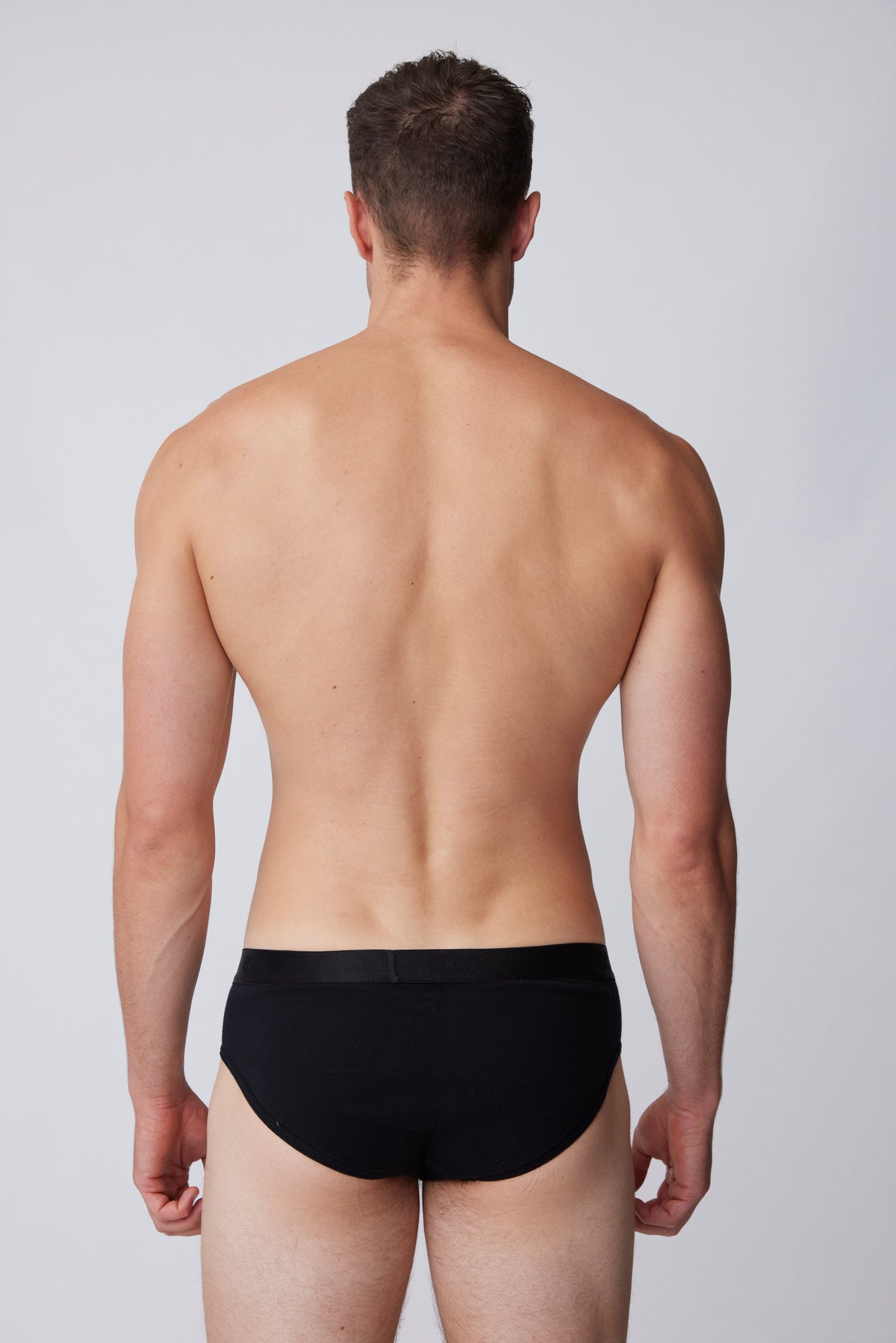 
            White, brunet male wearing only black brief from behind