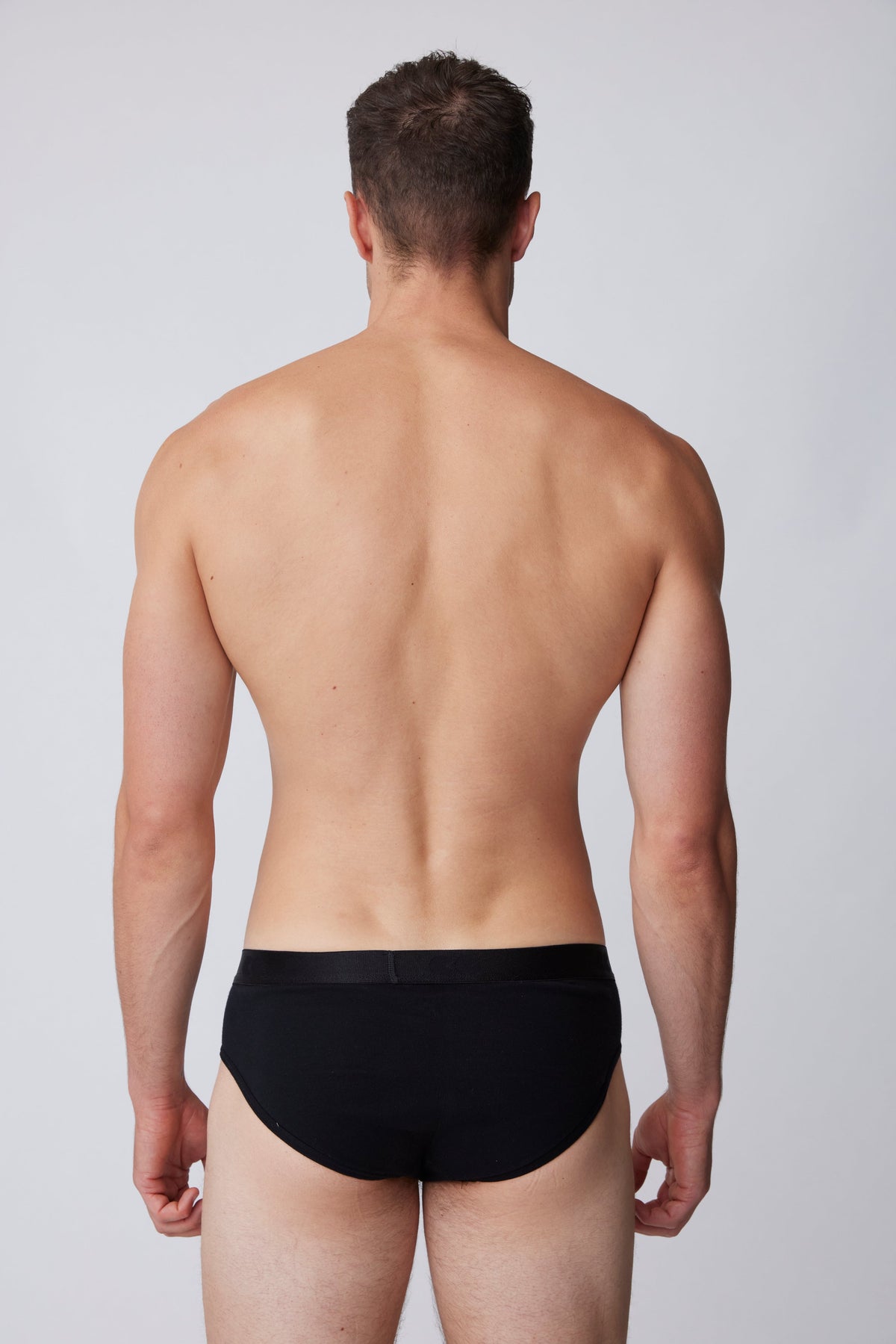 White, brunet male wearing only black brief from behind
